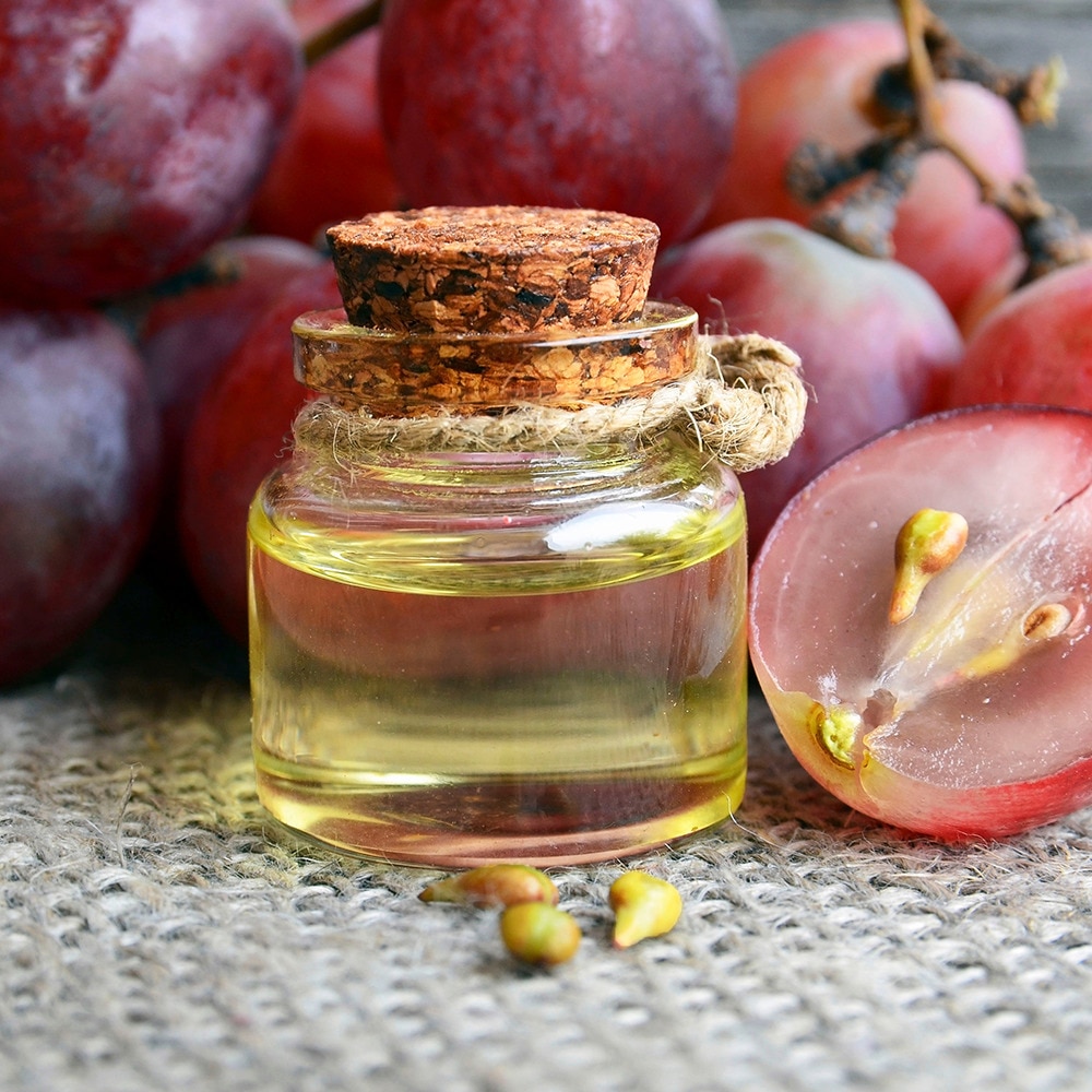 Grapeseed oil in a bottle with grapes in the backgrouund