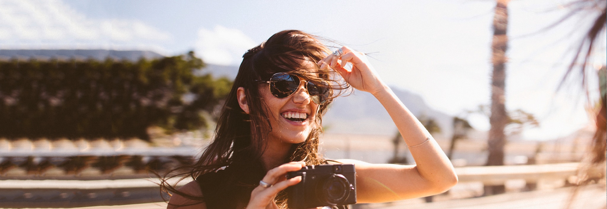 Una ragazza bruna con gli occhiali e i capelli al vento. 
