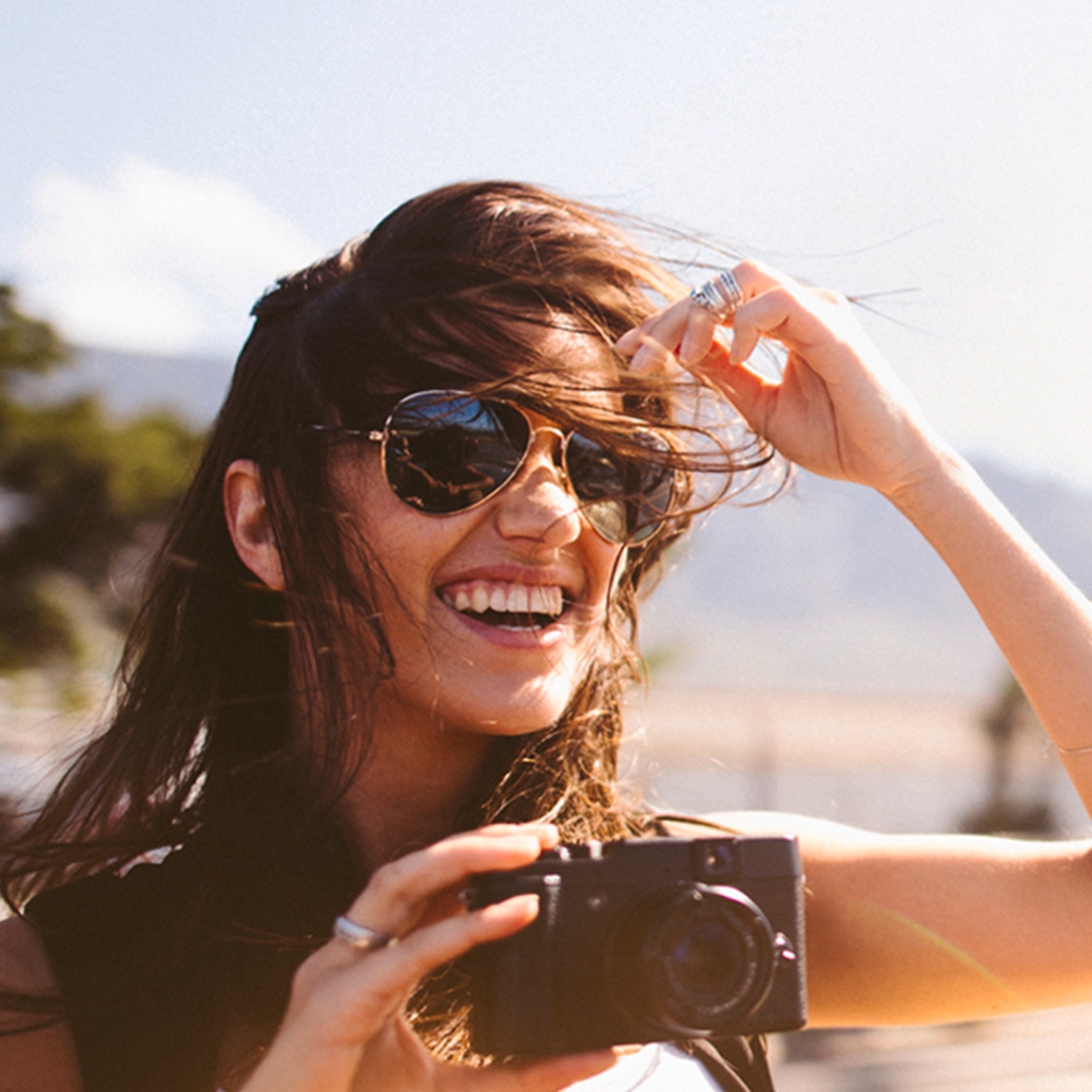Una ragazza bruna con gli occhiali e i capelli al vento.