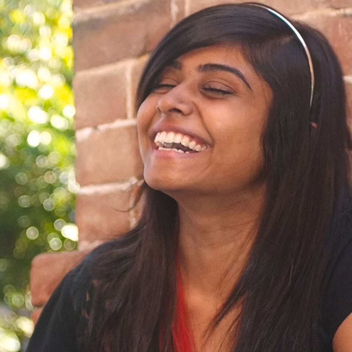 Two women sitting outside, laughing  and gently high-fiving each other.