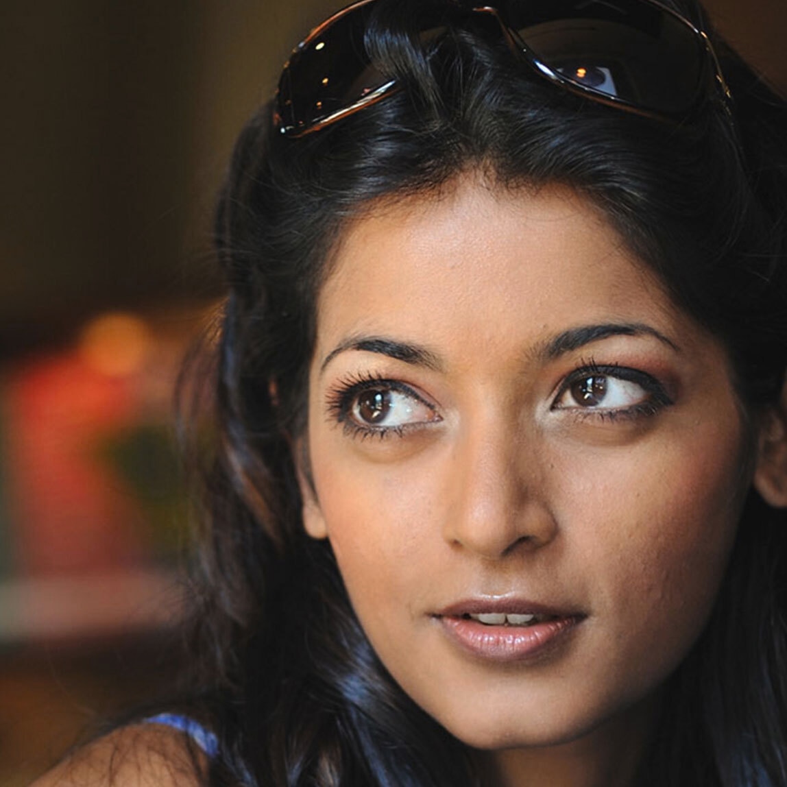 An intense looking woman with wavy dark hair staring off into the middle distance. 
