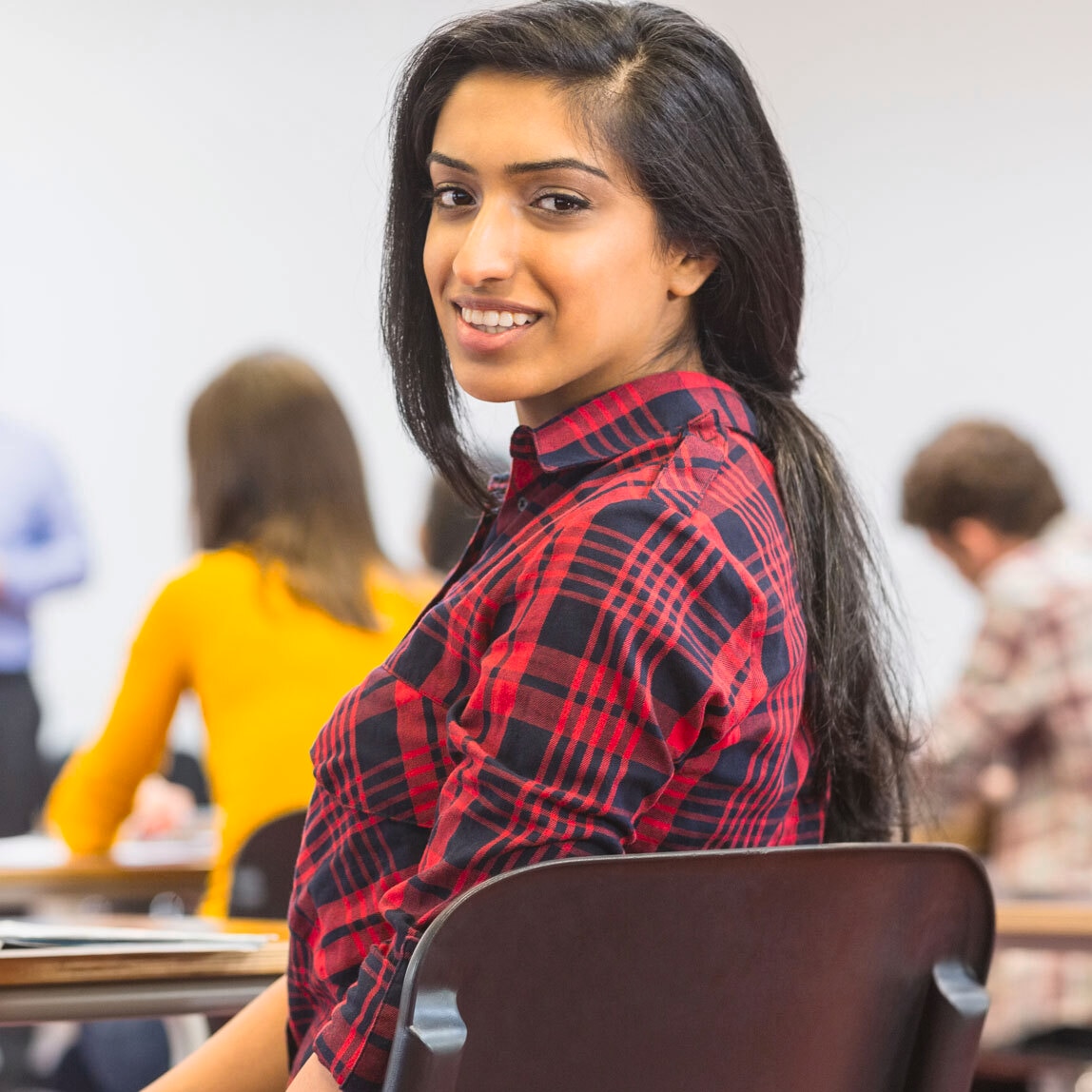 Woman with long dry hair, sitting on a chair looking over her shoulder and smiling.