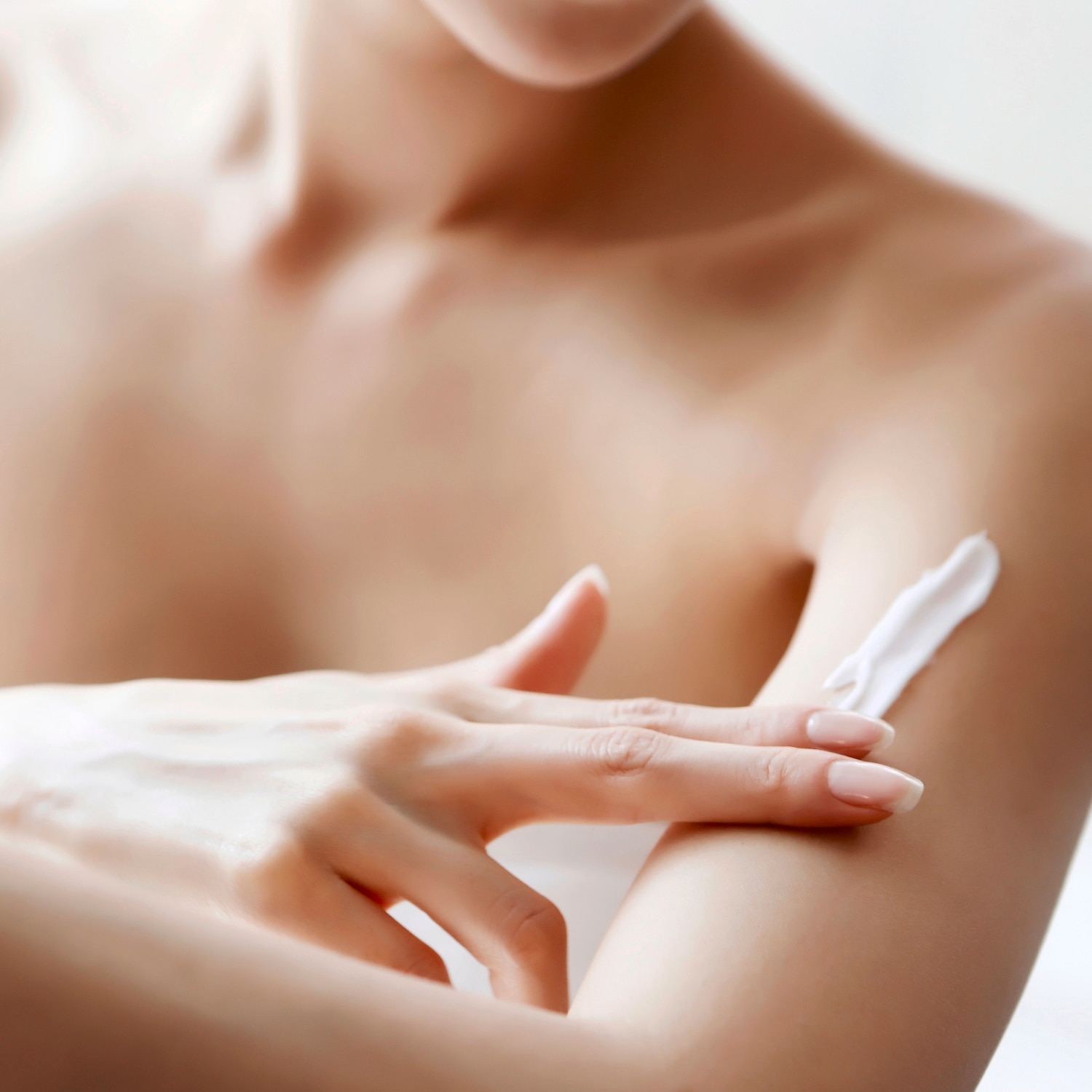 A person applying body lotion on upper arm.
