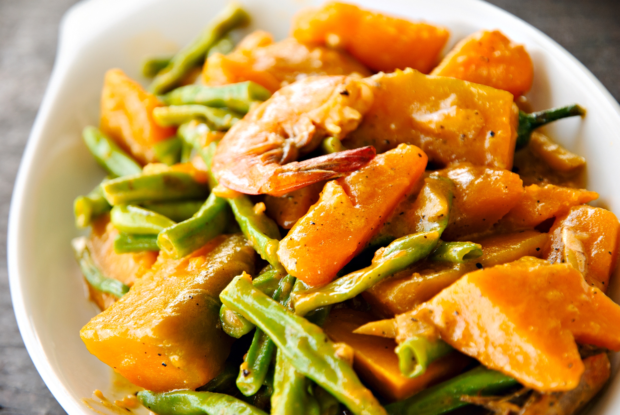 A huge serving of pumpkin, green beans, and shrimp cooked in coconut milk