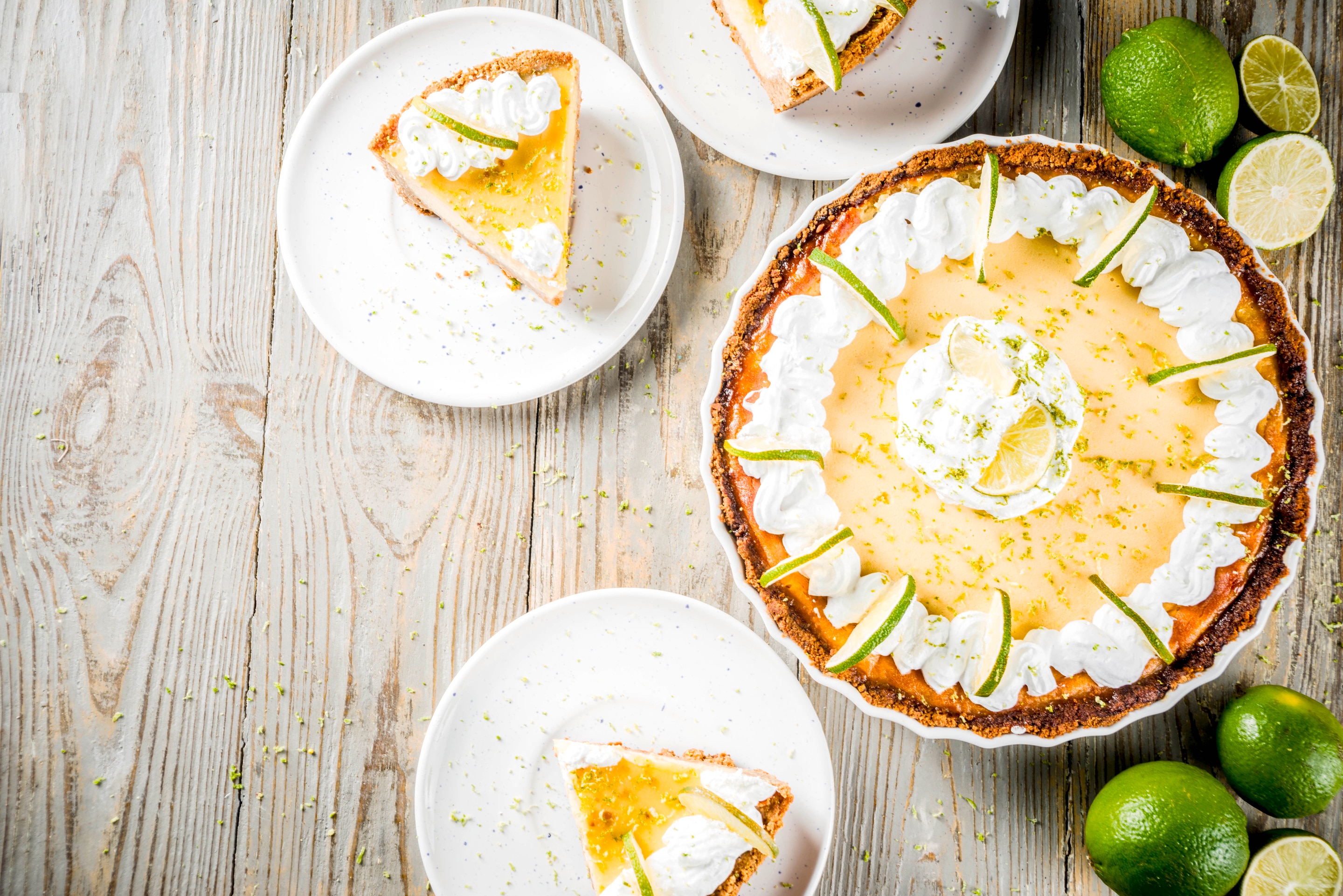 A Key Lime Pie and slices of it on a wooden table