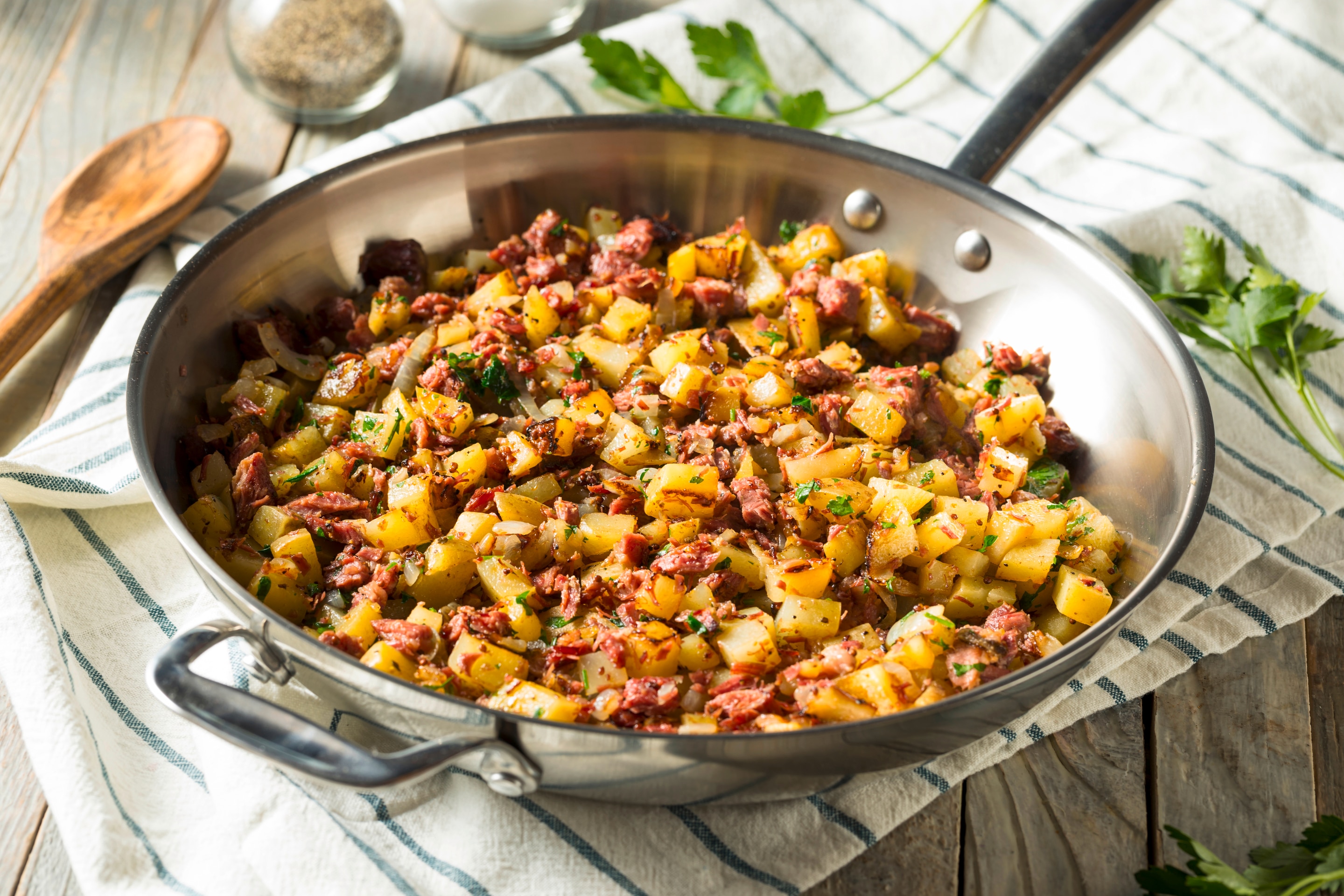 A pan of corned beef hash with potatoes and a generous sprinkling of parsley
