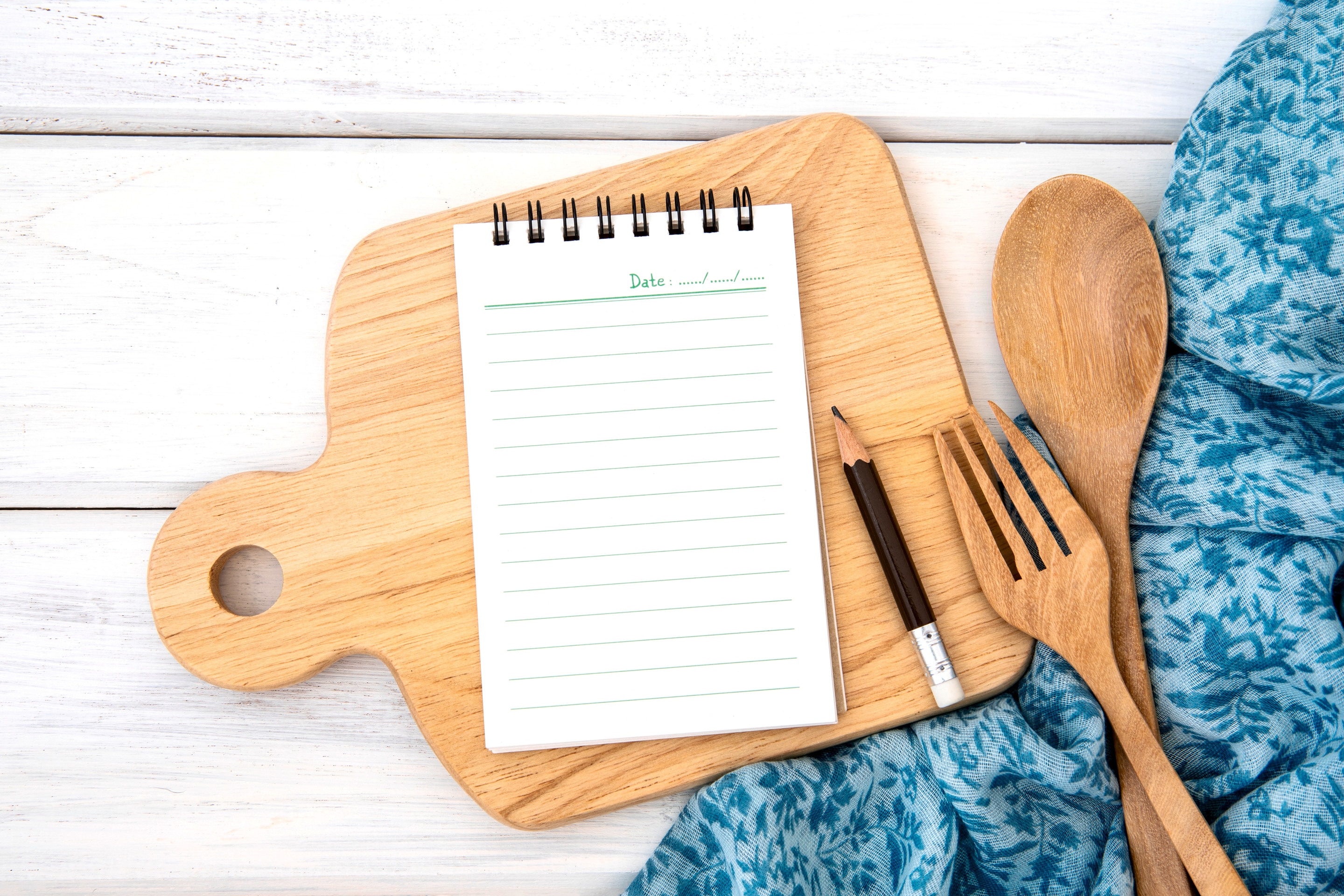 A note pad lies on a wooden chopping board
