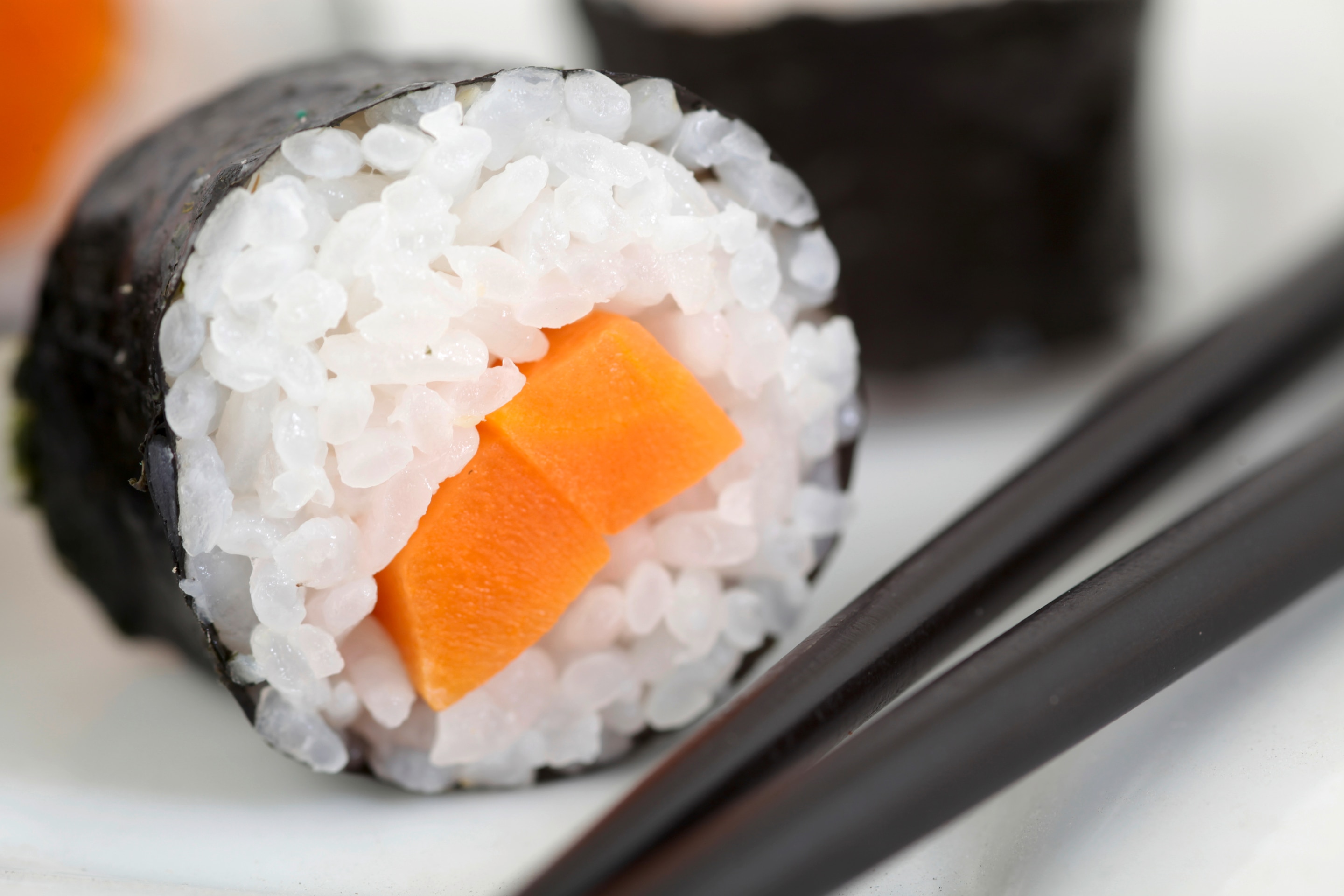 A close-up photo of a sushi roll filled with a carrot