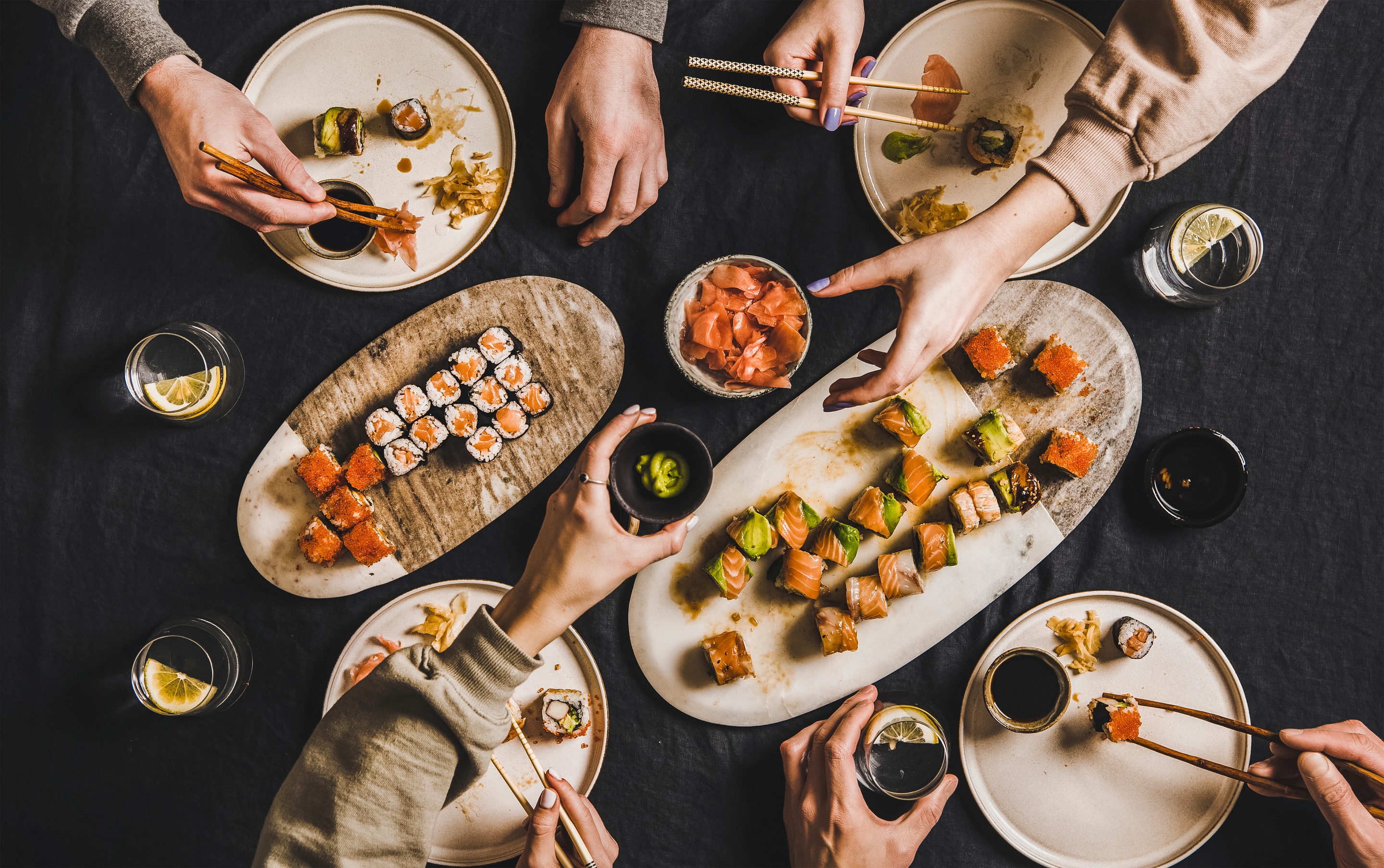 Four people dining on plates of Japanese sushi rolls