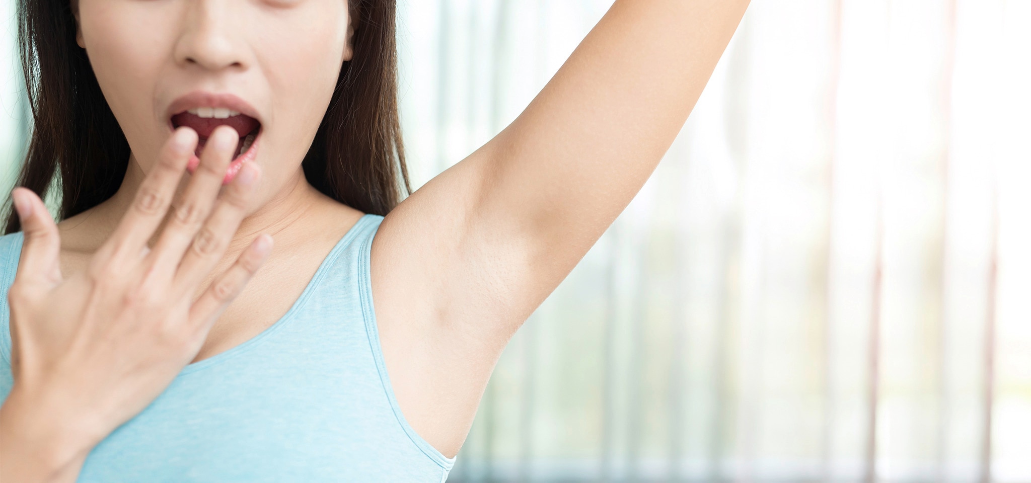 A woman showing off her armpit in a blue tank top