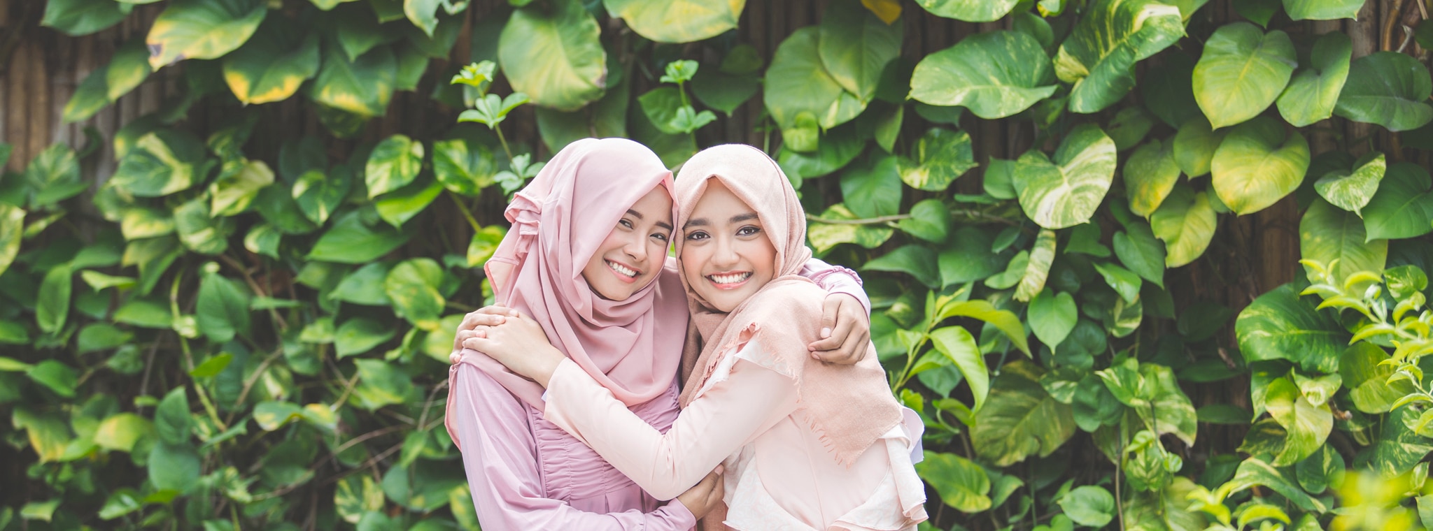 Two woman wearing hijabs, hugging each other
