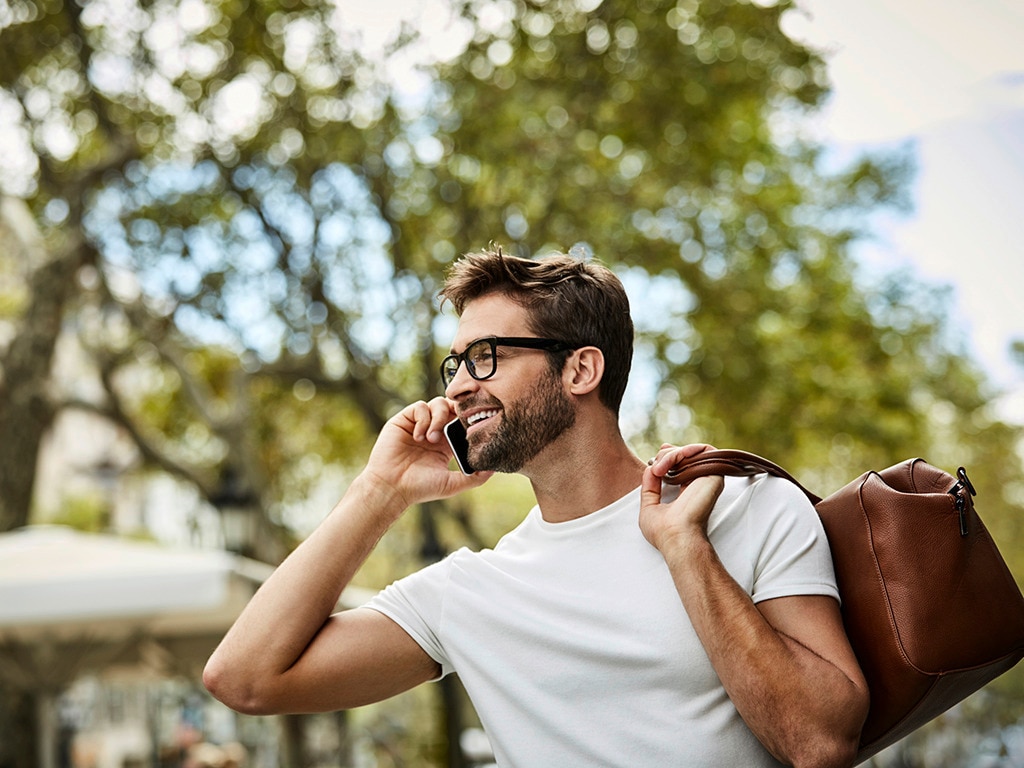 Hombre en el parque luciendo un peinado estilizado y hablado por celular