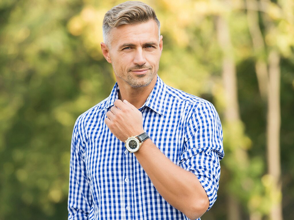 Hombre con pelo rubio y blanco, pasando de manera clásica en el parque 