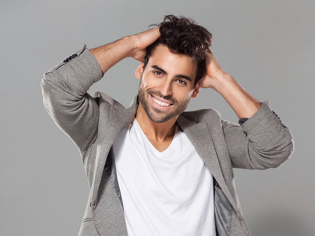 Hombre con pelo ondulado con las manos en la cabeza