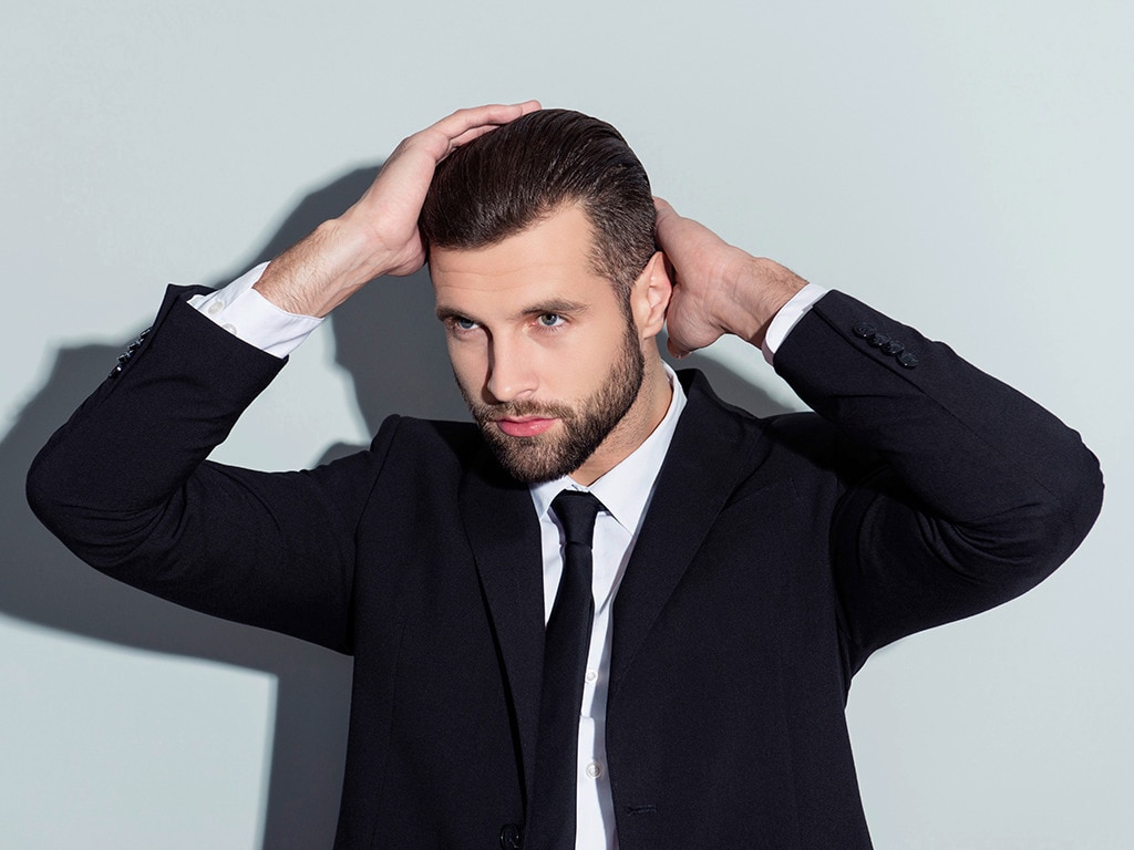 Hombre clásico con pelo corto arreglando su look con ayuda de sus manos 