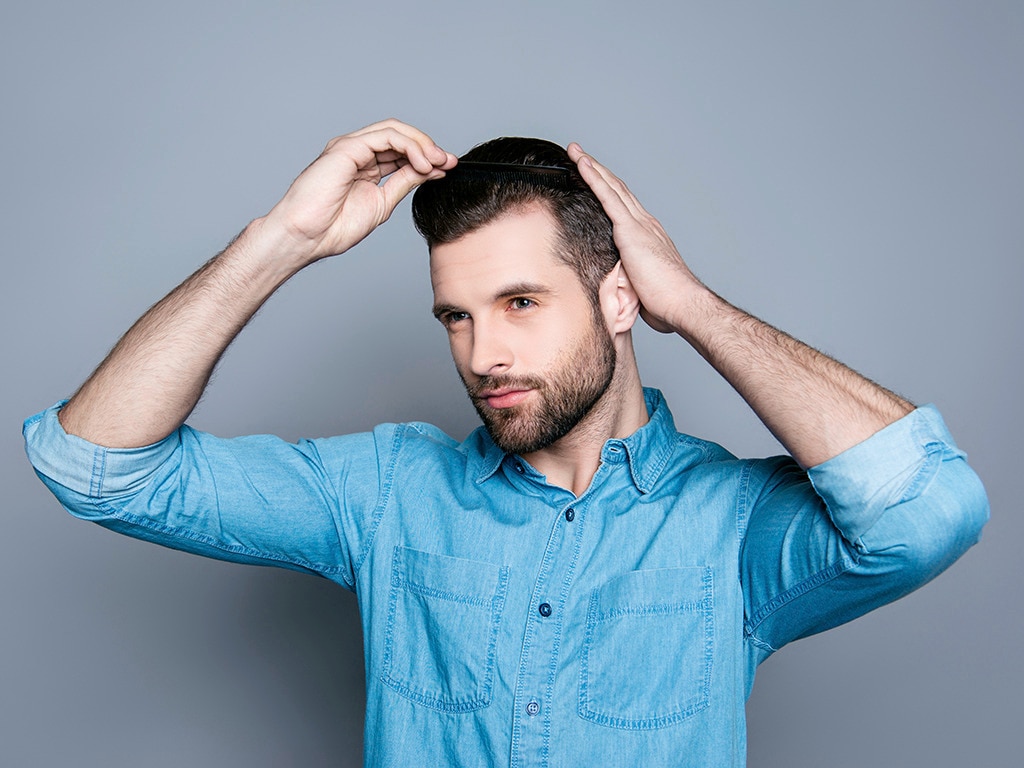 Hombre moderno con pelo corto arreglando su look con ayuda de sus manos 