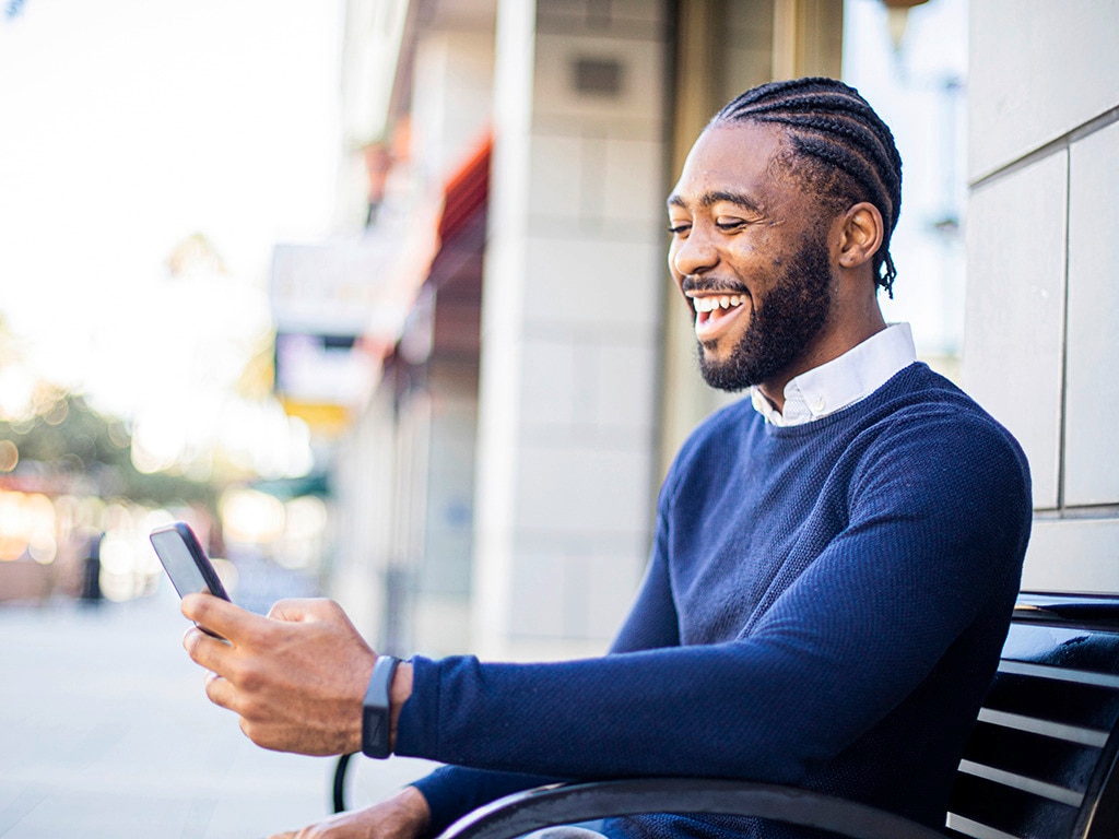 Hombre con trenzas africanas comunicándose desde su celular, utilizando un traje ejecutivo