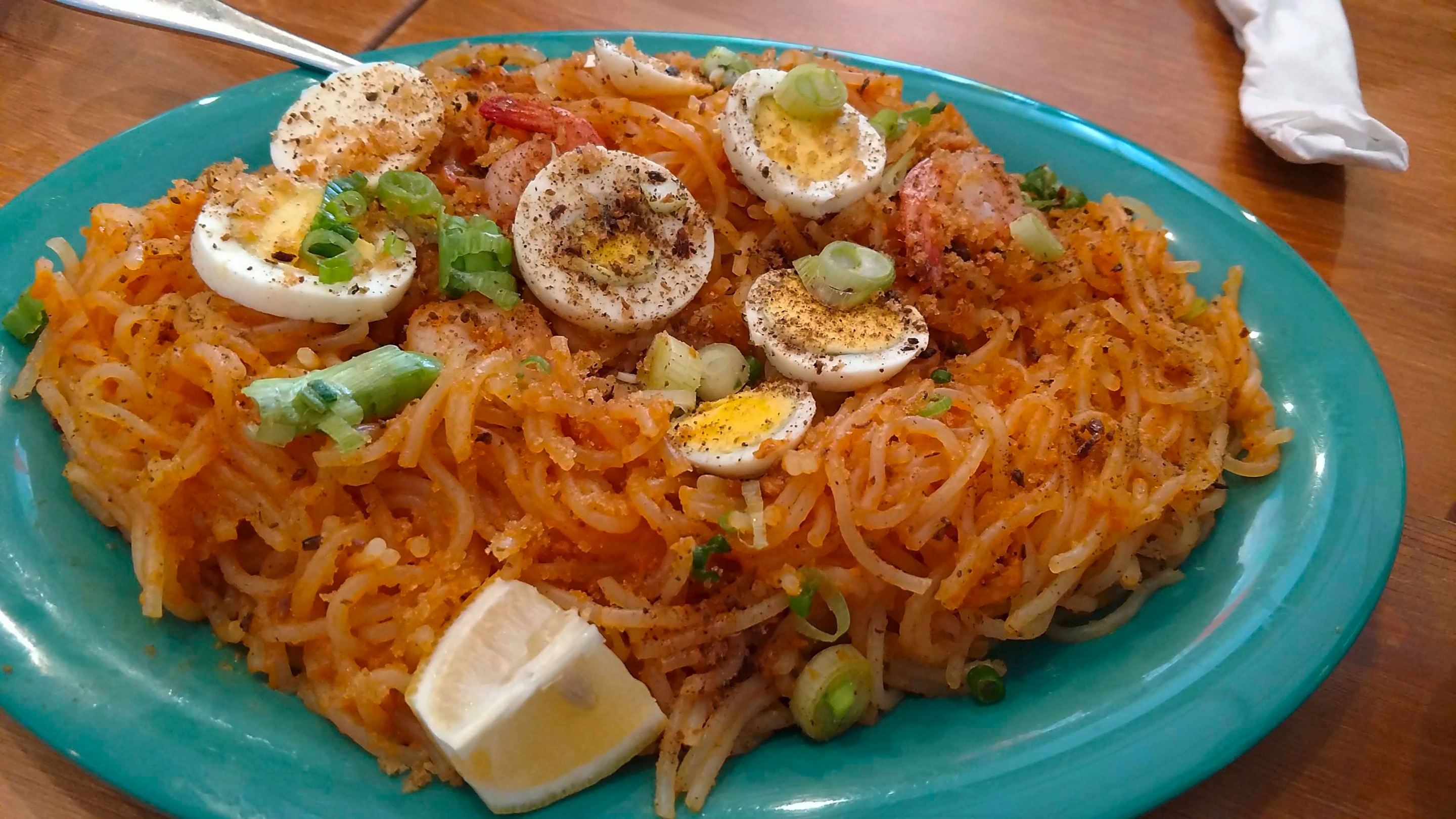 A large dish of spaghetti palabok topped with hard-boiled eggs, chicharon, and cooked shrimp