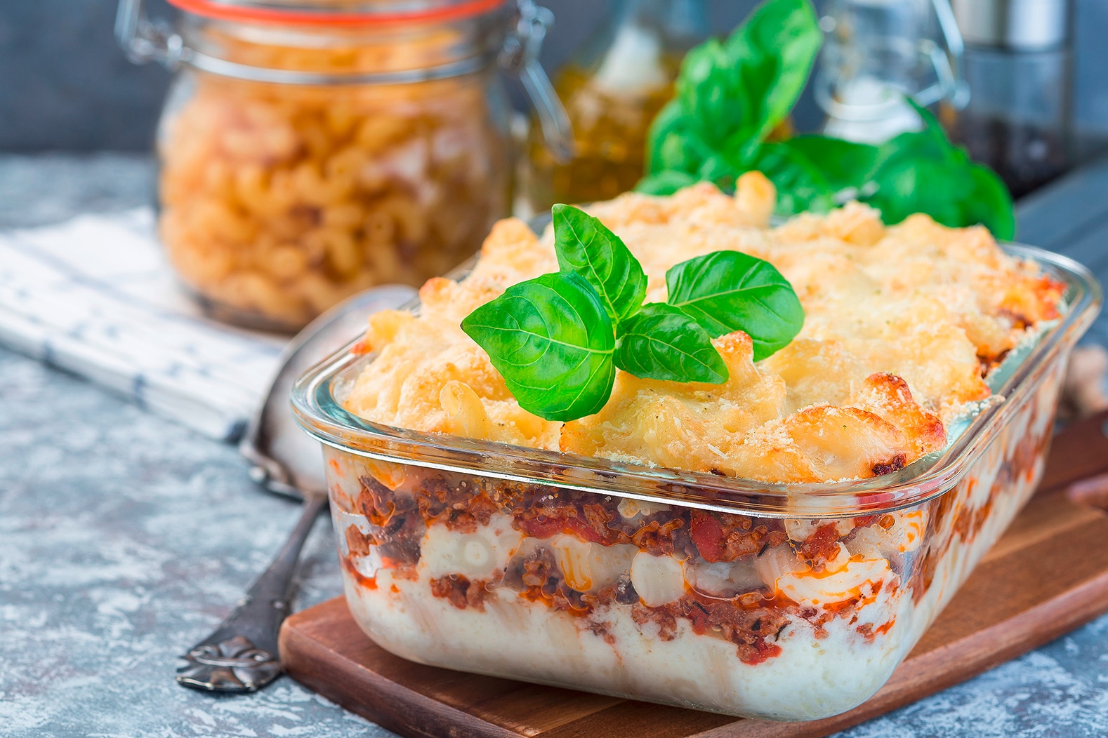 Baked macaroni with bechamel sauce in a glass baking dish, garnished with basil leaves