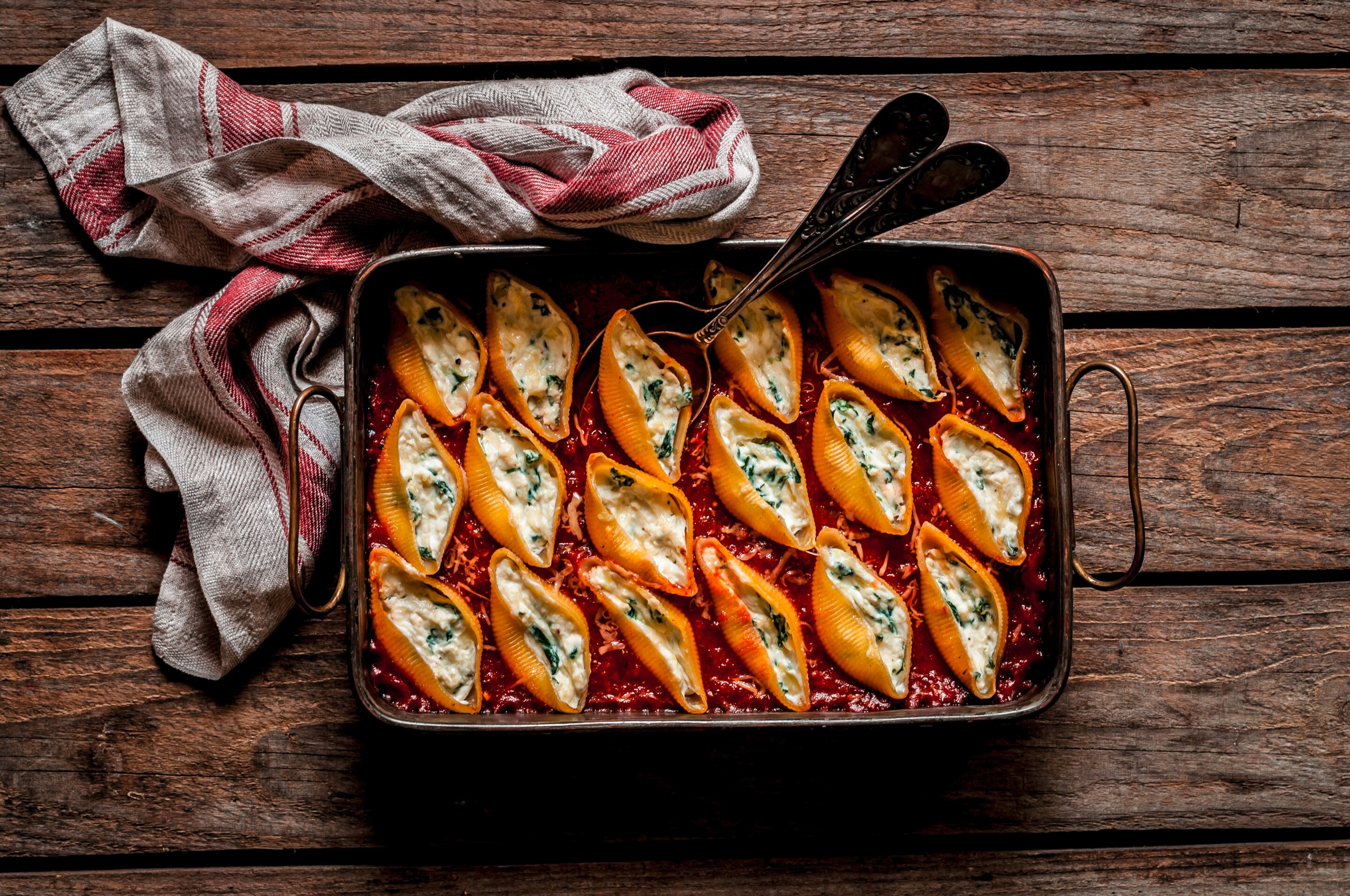 A pan of stuffed pasta shell noodles baked in red meat sauce