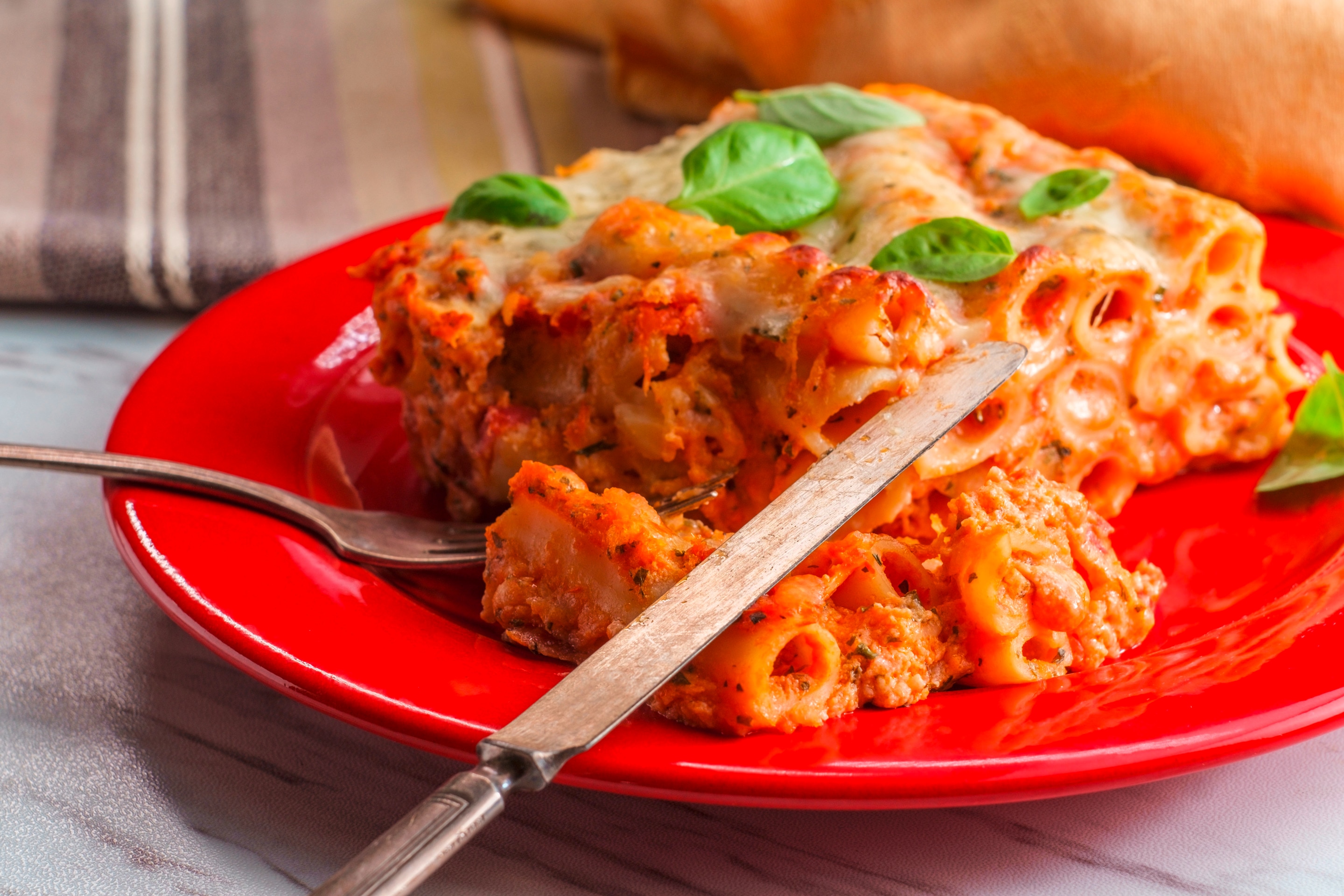 A serving of baked ziti with basil leaves for garnish