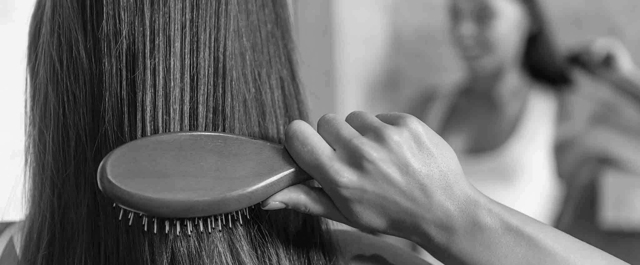 Una mujer cepillándose su cabello liso.