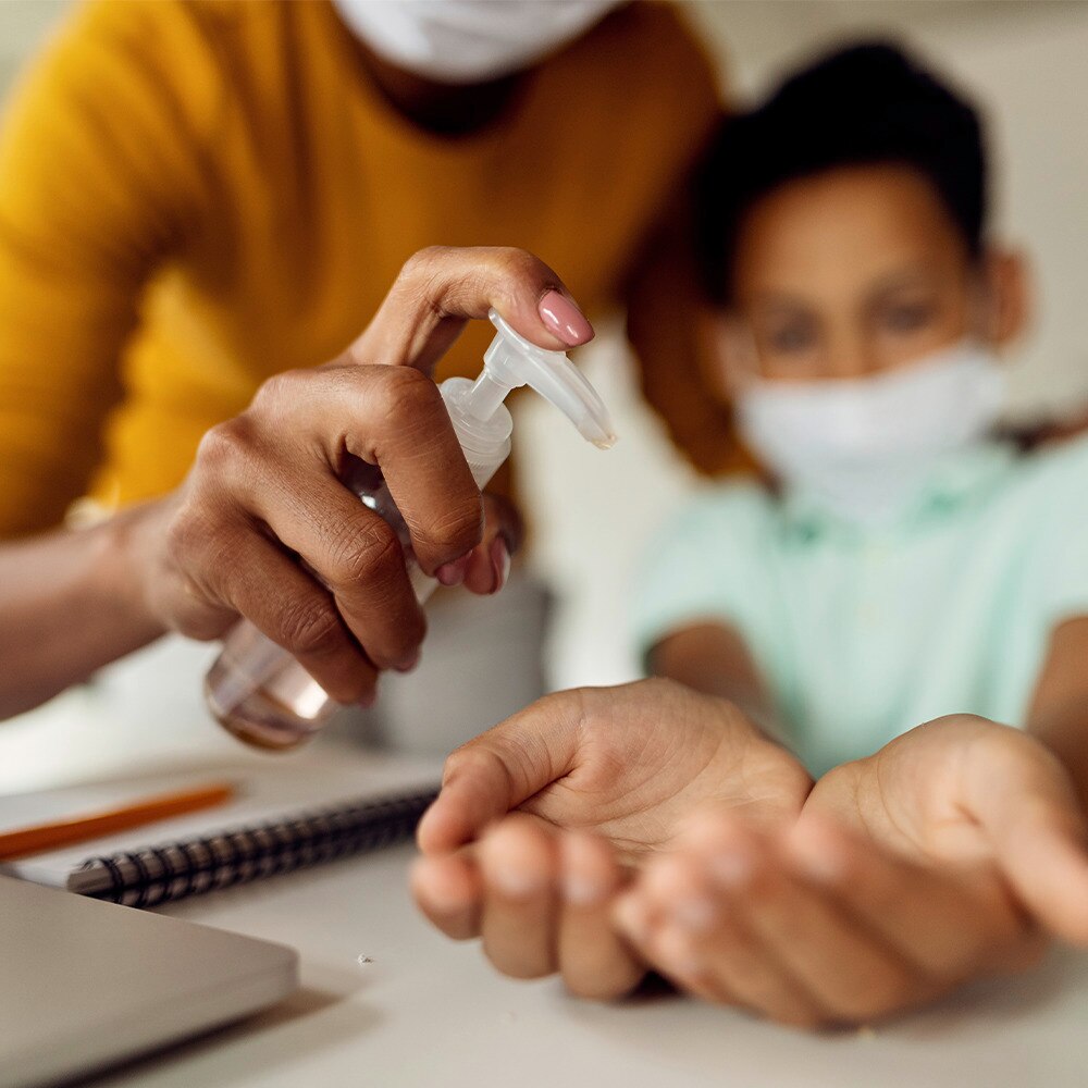 Adult applying hand sanitiser on little kid's hands