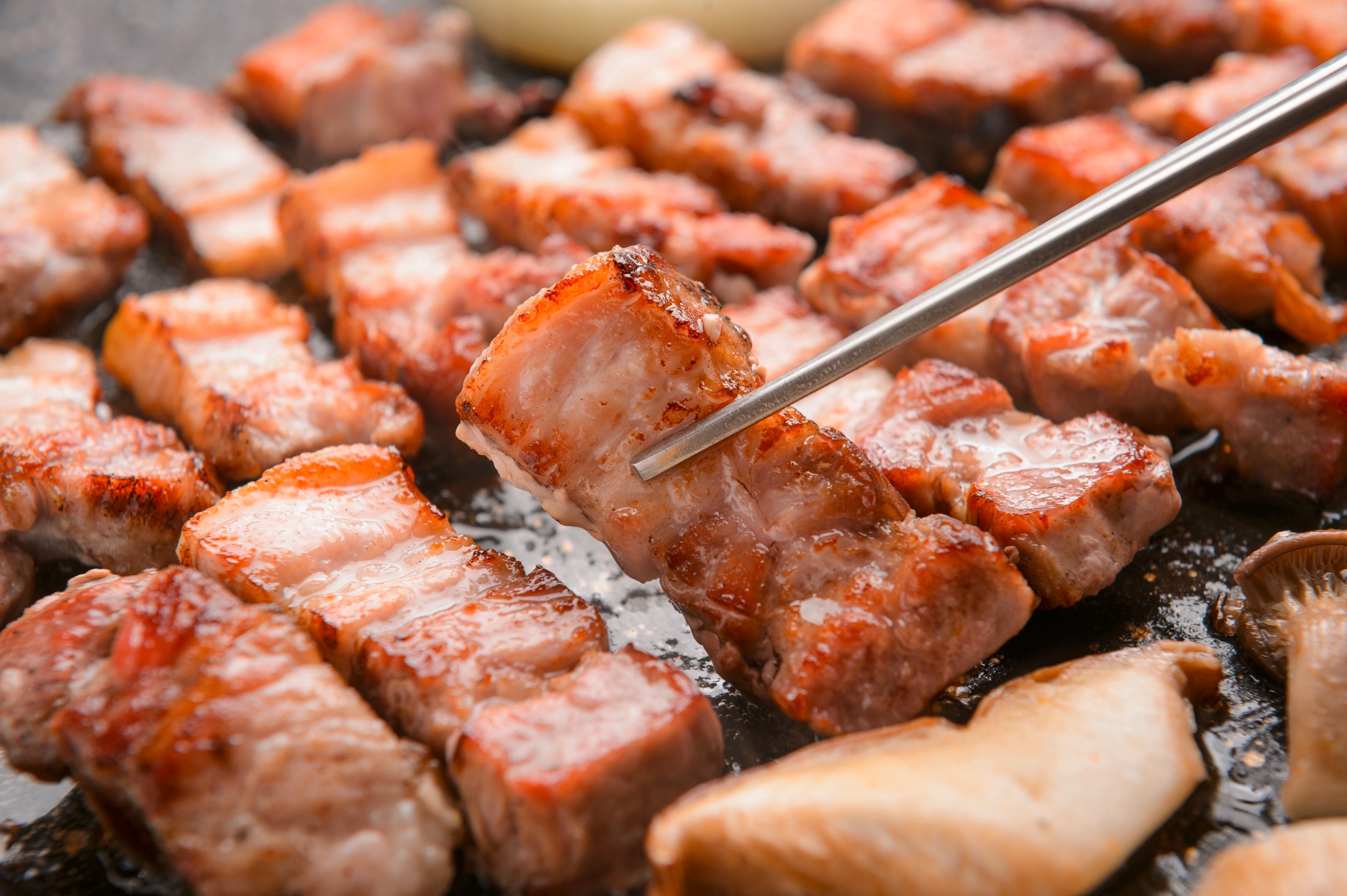 Slices of cooked Korean pork belly on a stovetop grill