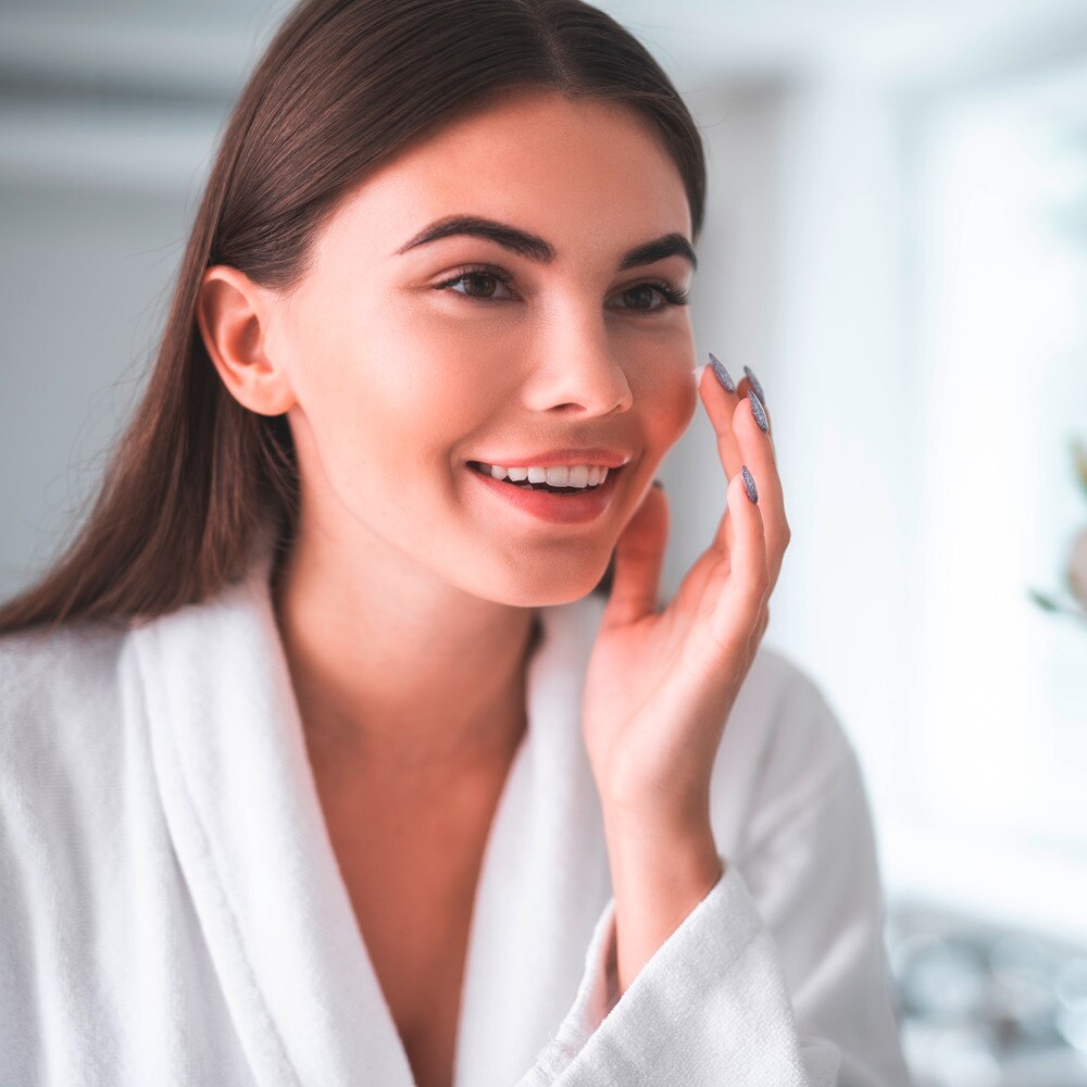 Lady appyling lotion on her cheek