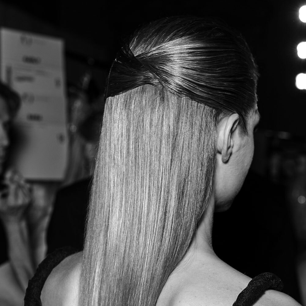 The back of a female model's head. her long brown hair is gathered into a large chic bow.