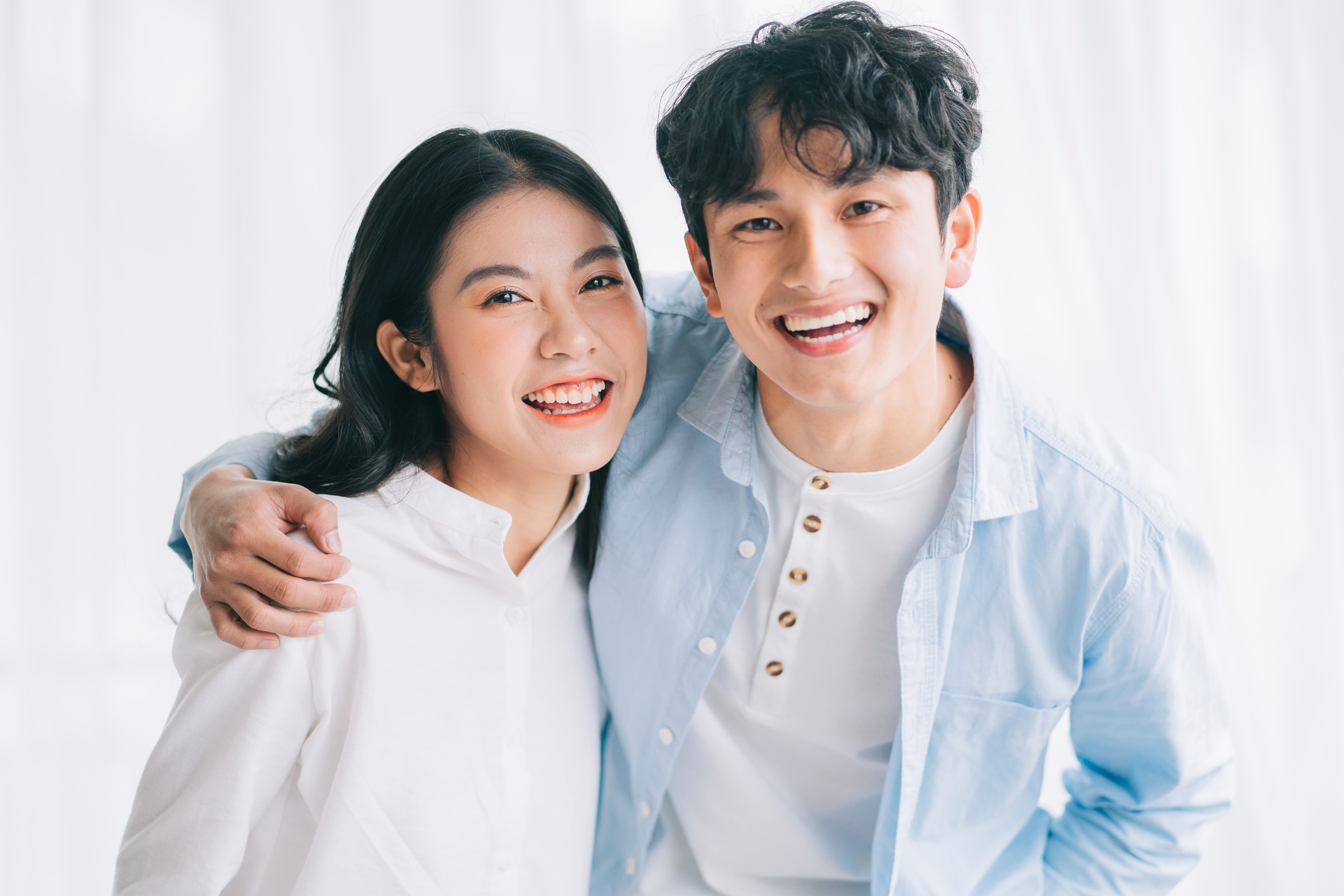 Pasangan kekasih berwajah Asia sedang tertawa bahagia.