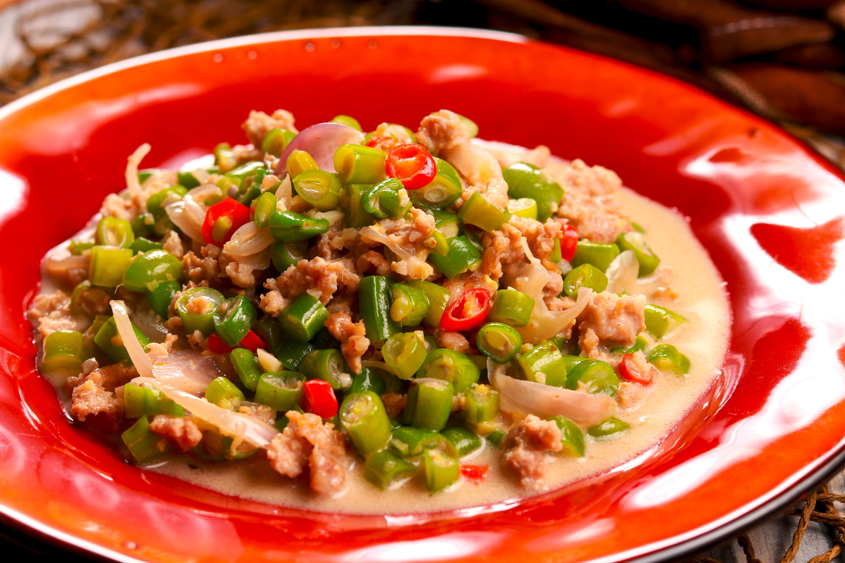 A plate of pork and beans with spicy coconut sauce