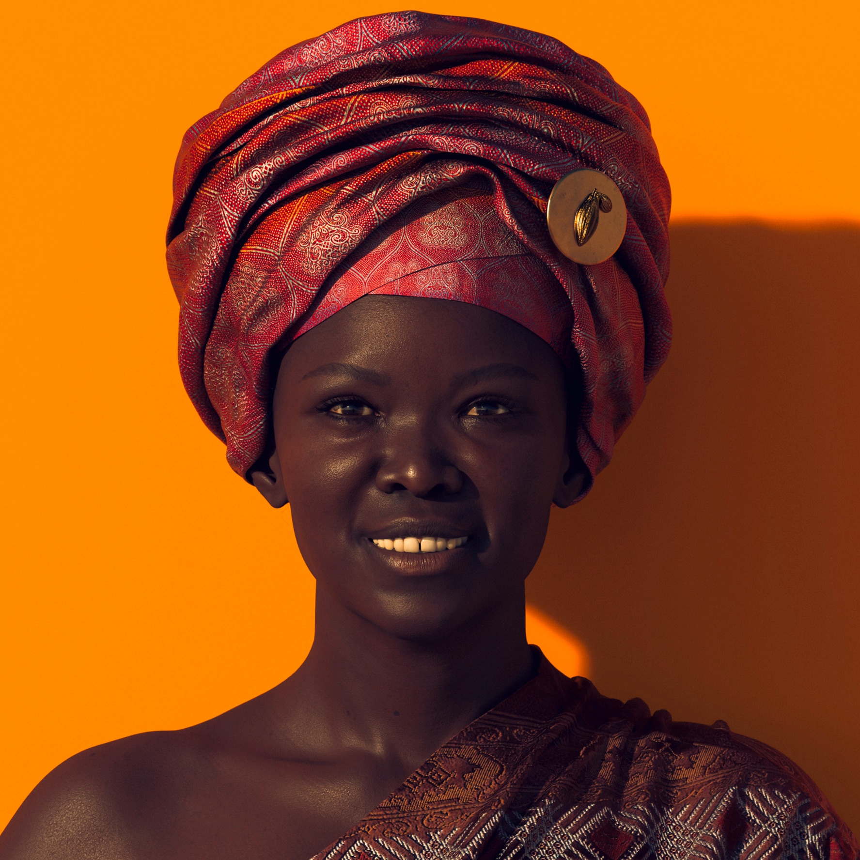 Porträt einer afrikanischen Frau, die ein großes Tuch um den Kopf gewickelt hat, auf orangenem Hintergrund