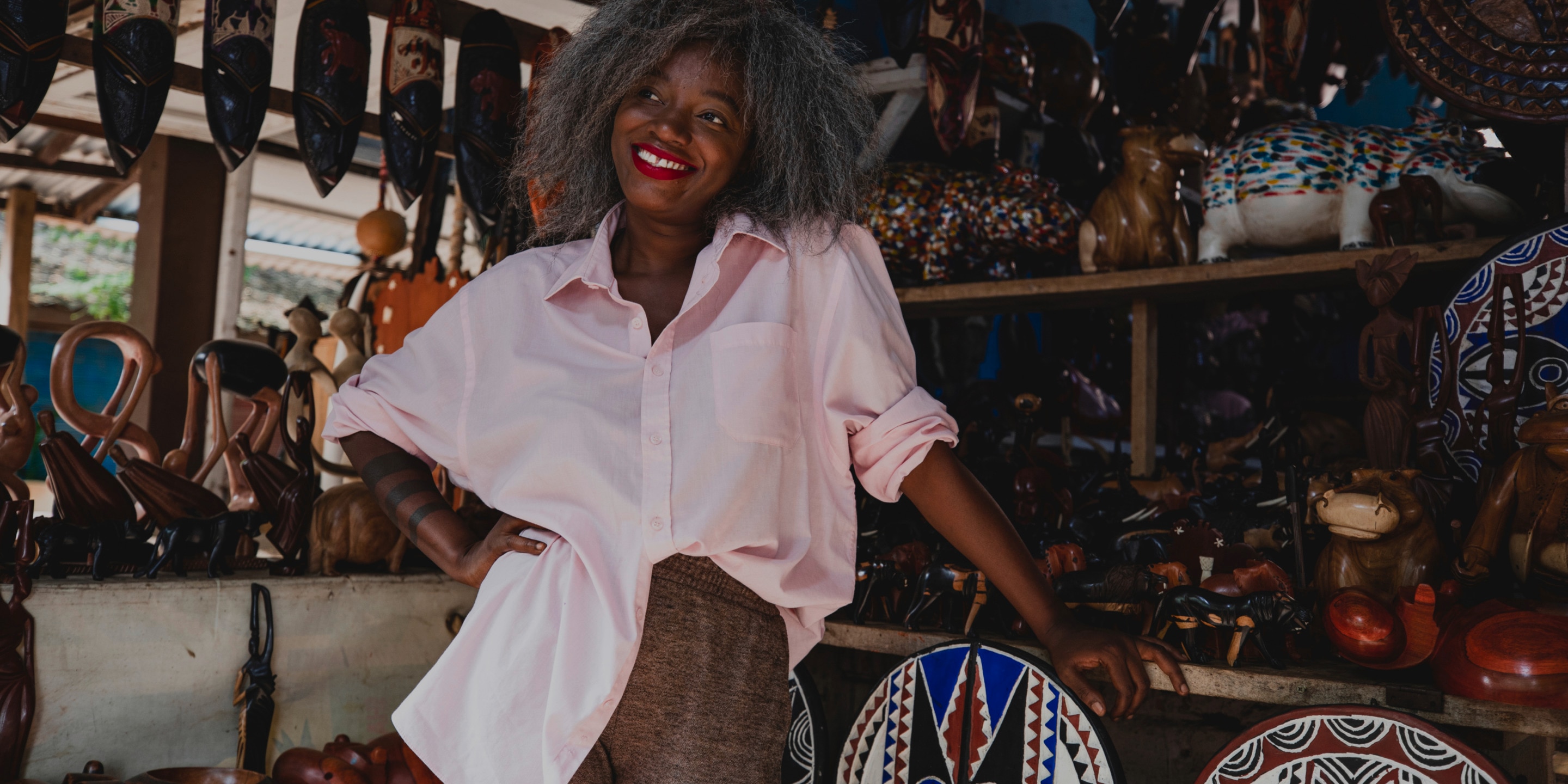 La diseñadora de moda Rebecca Zoro sonriendo - en una tienda de souvenirs africana dentro de una comunidad agrícola de cacao de Costa de Marfil