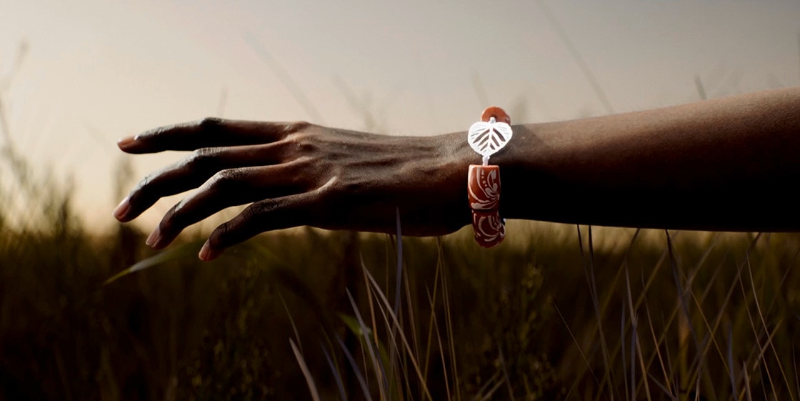 Afrikanische Frau mit Armband in der Hand, die über das lange Gras streicht