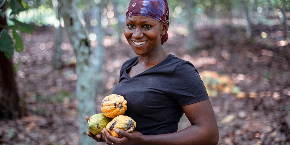Smiling woman cocoa farmer holding three cocoa pods
