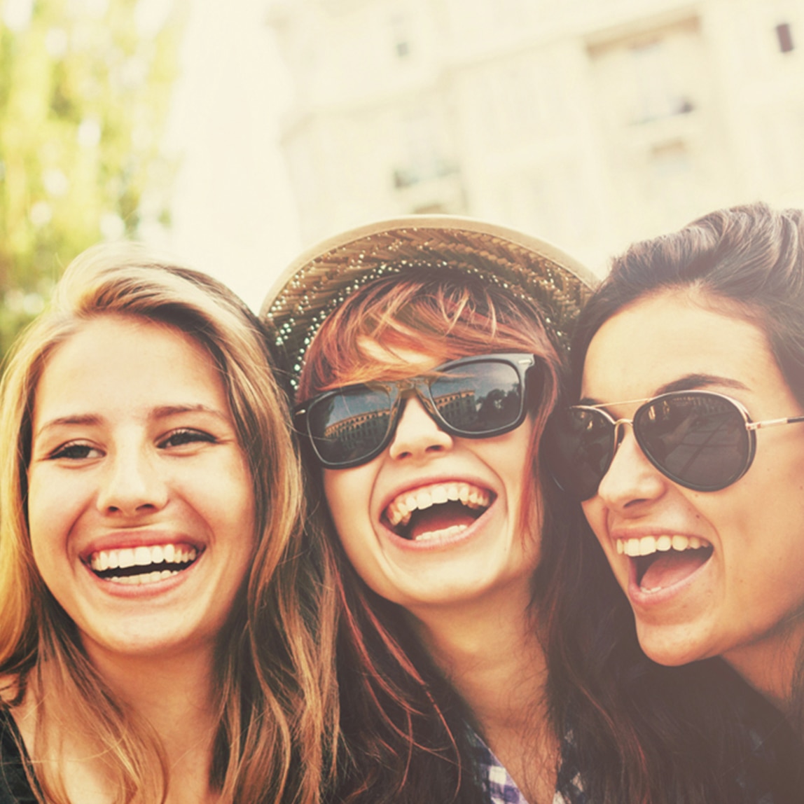 ثلاث فتيات يقمن بالتقاط صورة والابتسامة تزين وجوههن 