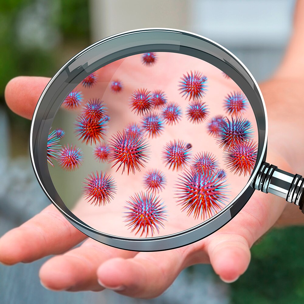 Magnifying glass zooming in on hand with germs