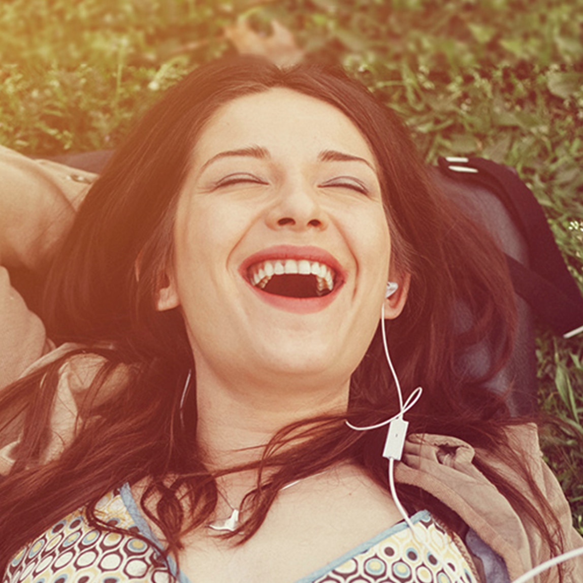 فتاة مستلقية على العشب وتستمتع بالموسيقى بينما تضع يدها خلف رأسها
