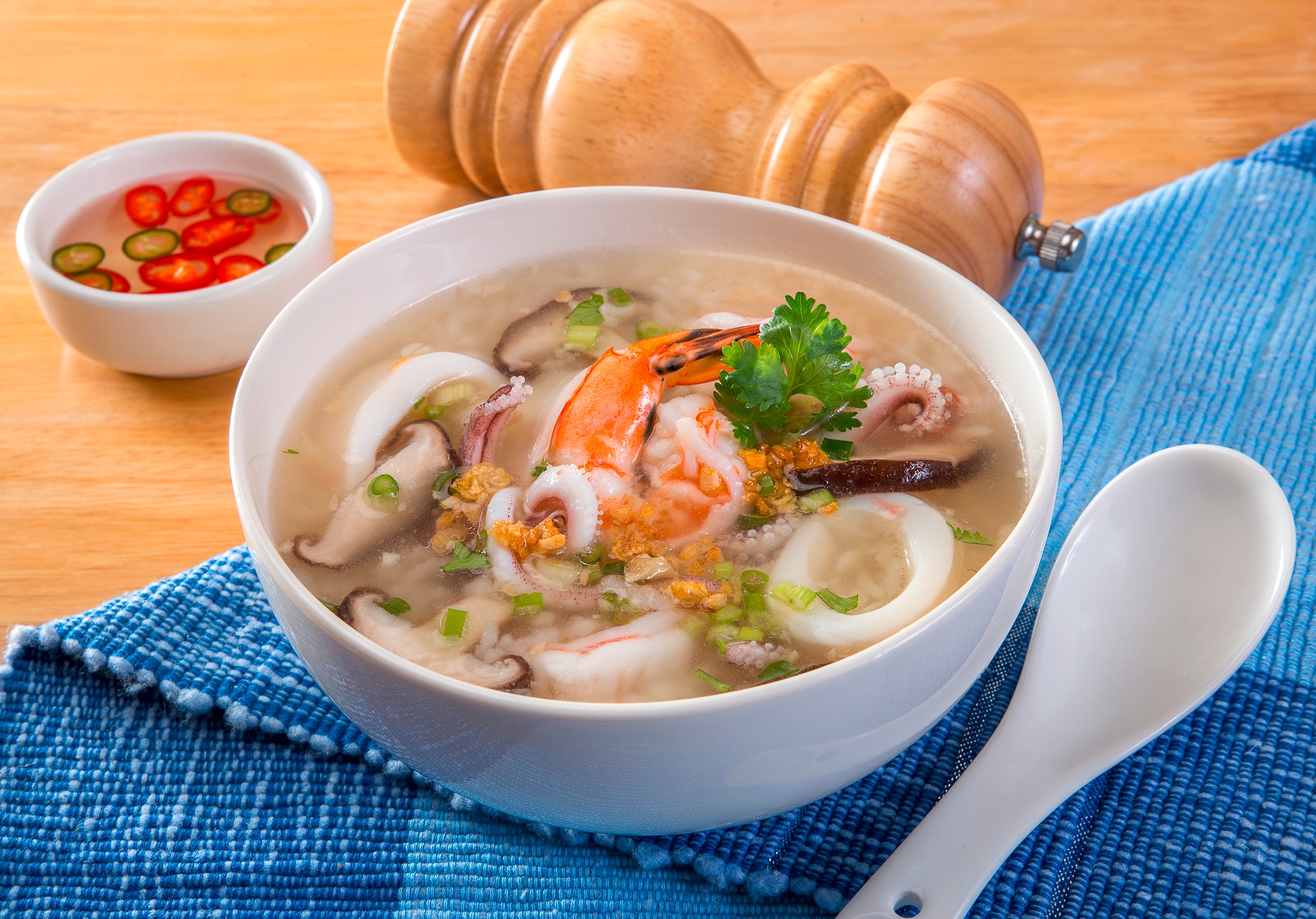 A bowl of seafood congee with squid, shrimp, and mushrooms