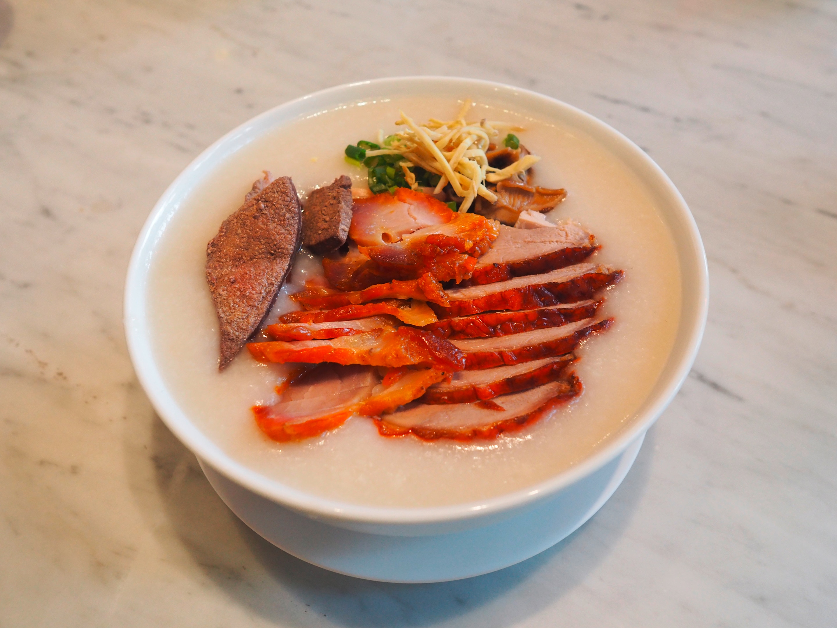 Roasted duck slices over a large serving of congee