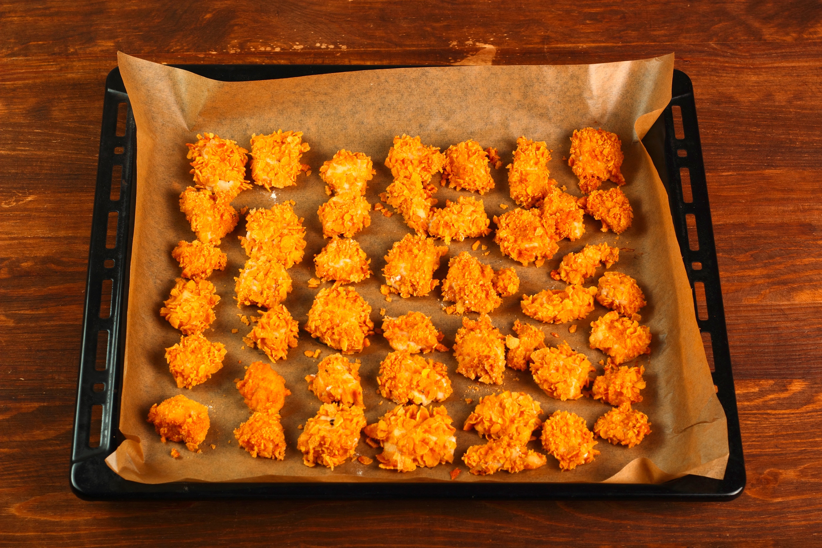 Baking tray lined with parchment paper full of chicken nuggets