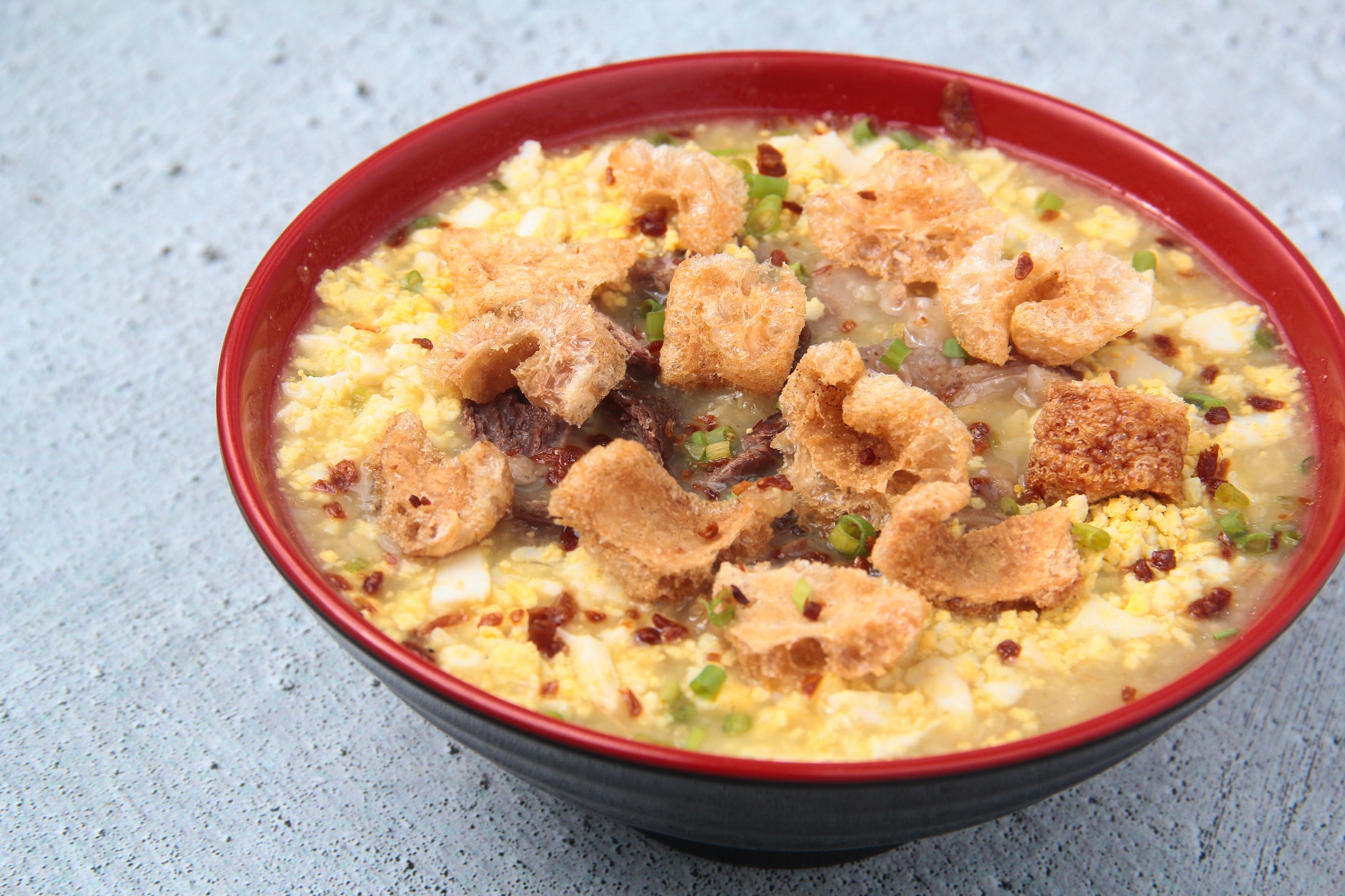 Chicharon pieces topped over a large bowl of tasty lugaw