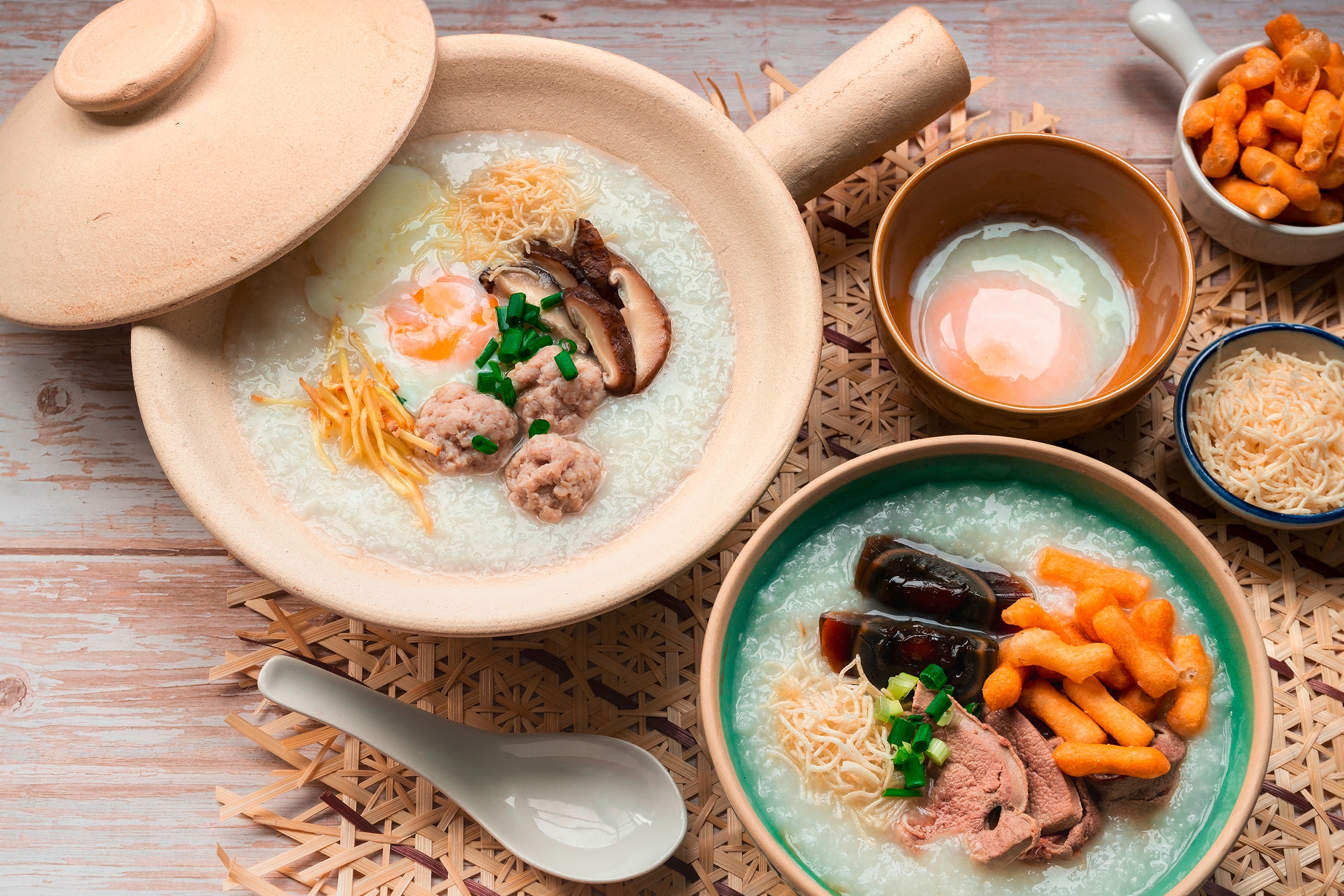 Several bowls of rice porridge topped with proteins, eggs, and veggies