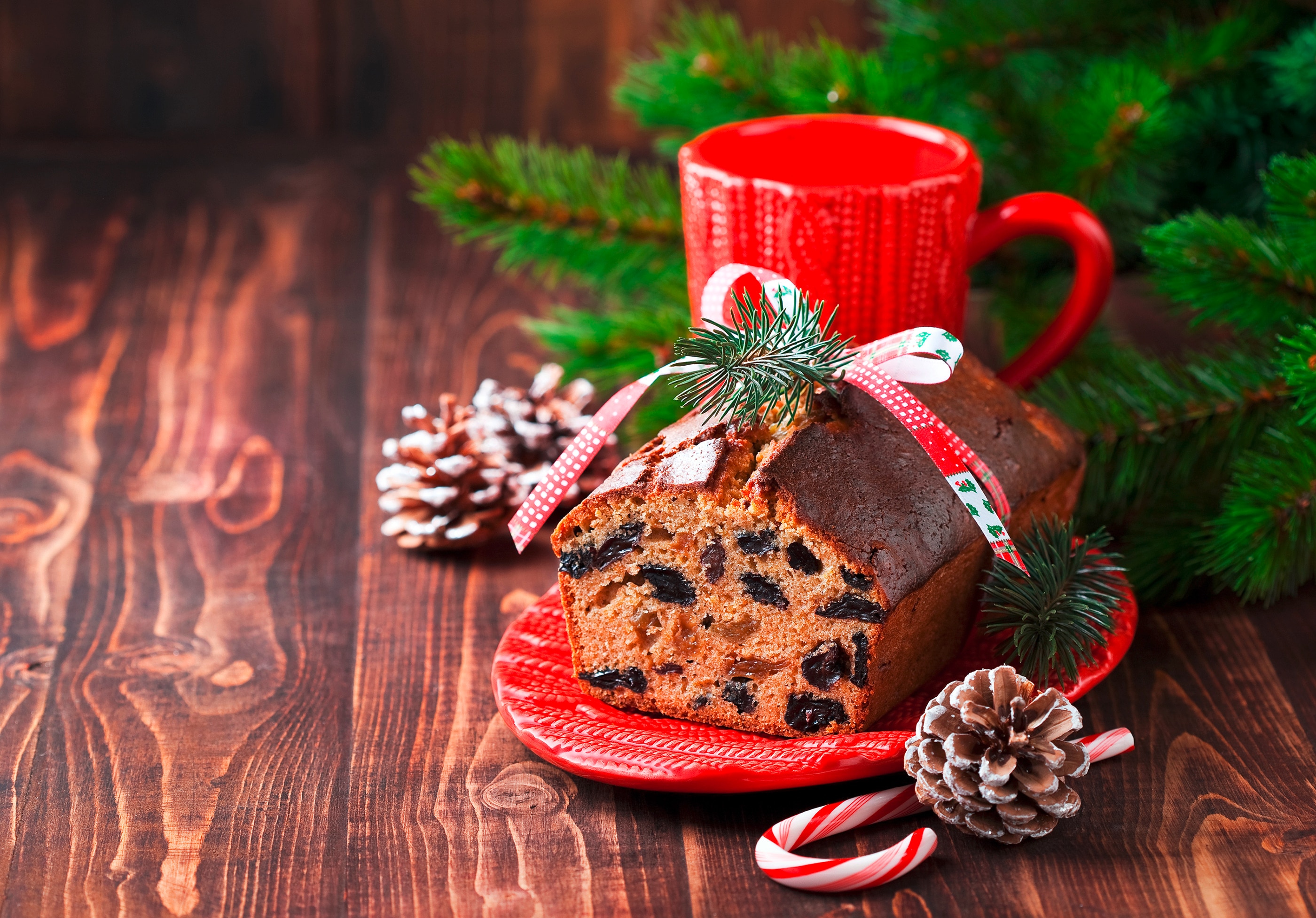 A loaf of fruitcake served on a red plate with Christmas ornaments