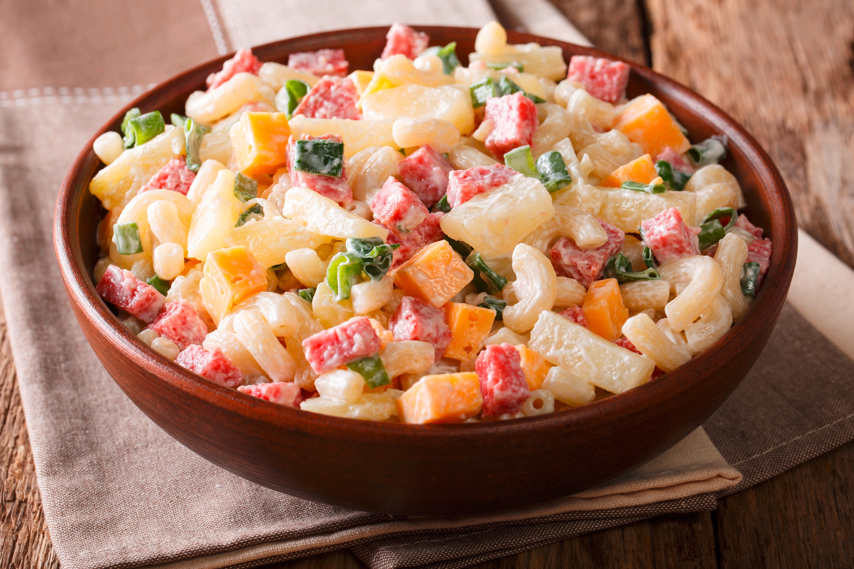 A bowl of macaroni salad with ham, cheese, and bell peppers