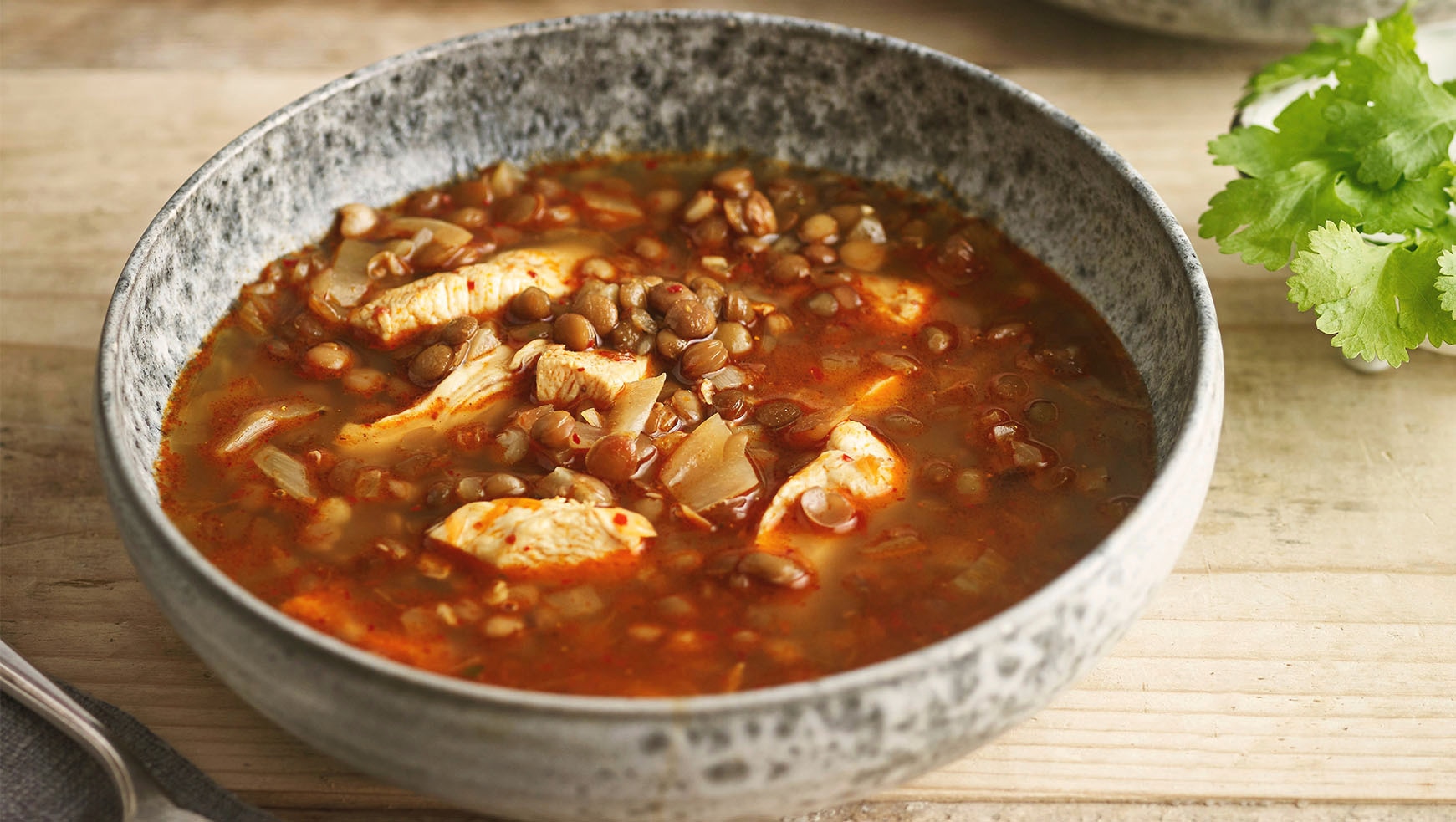Lentil & Chicken soup in a bowl with corrainder on the side