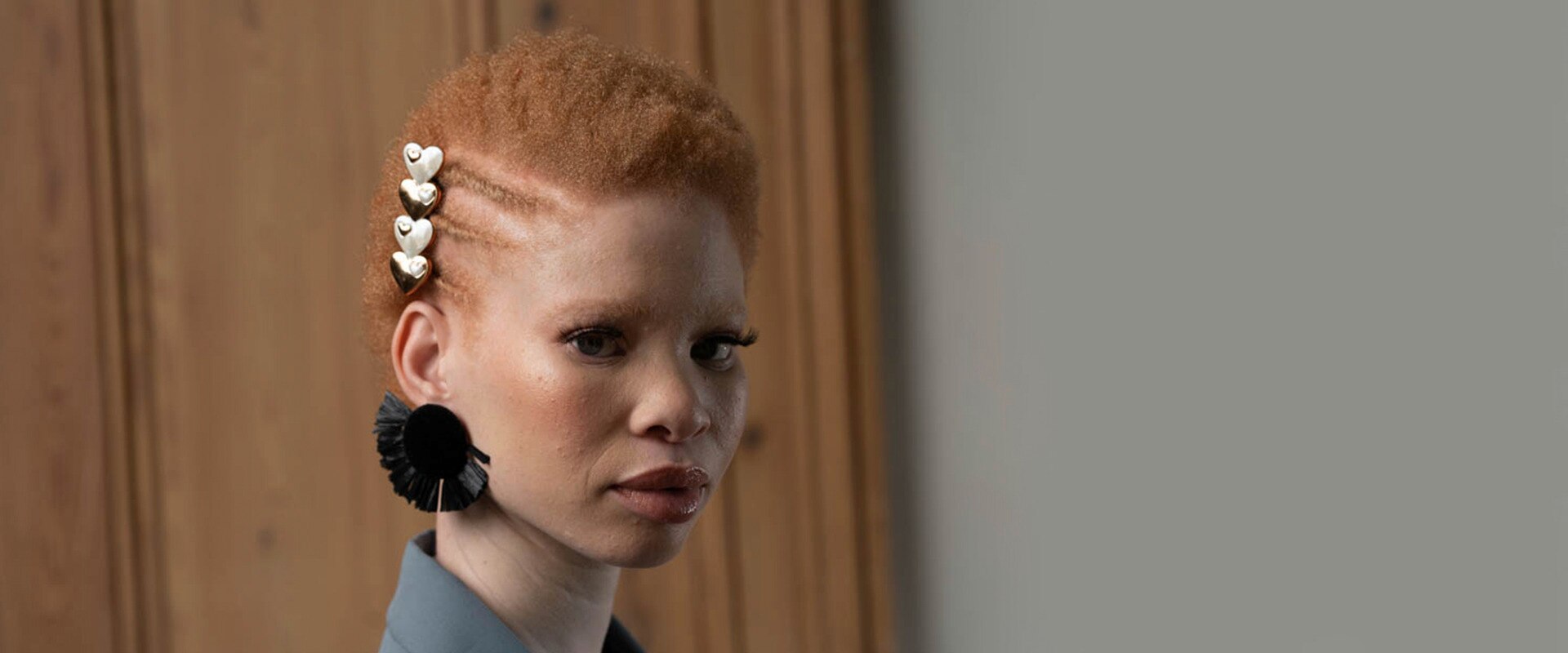 Model with natural afro hair with a side twist on the left side of her head. Model is wearing red lipstick and large hanging earrings