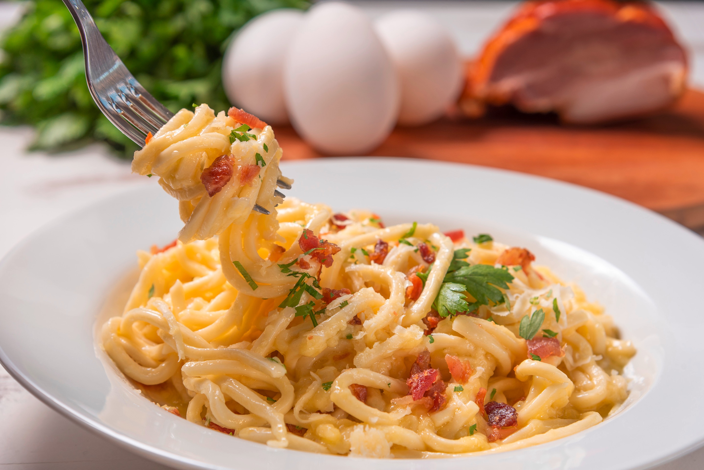 A plate of creamy carbonara with parsley and bacon bits
