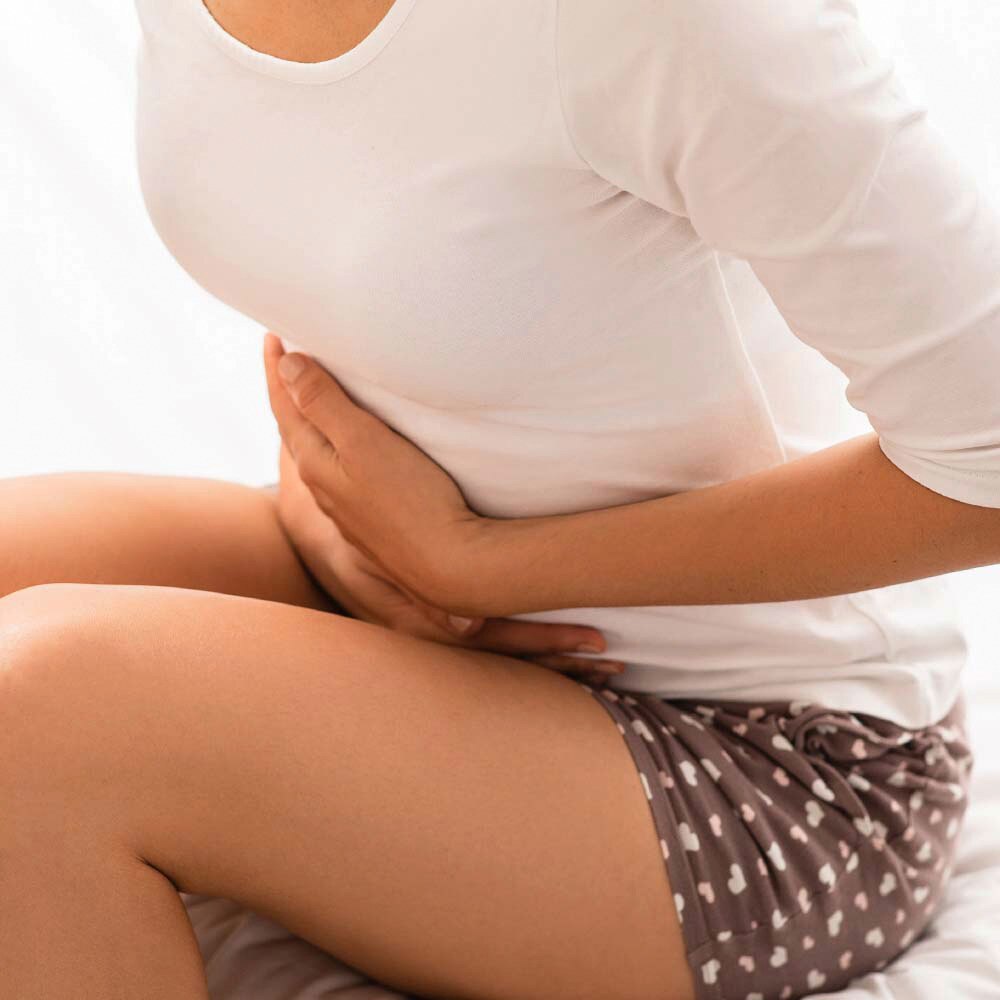 Lady sitting down holding her stomach